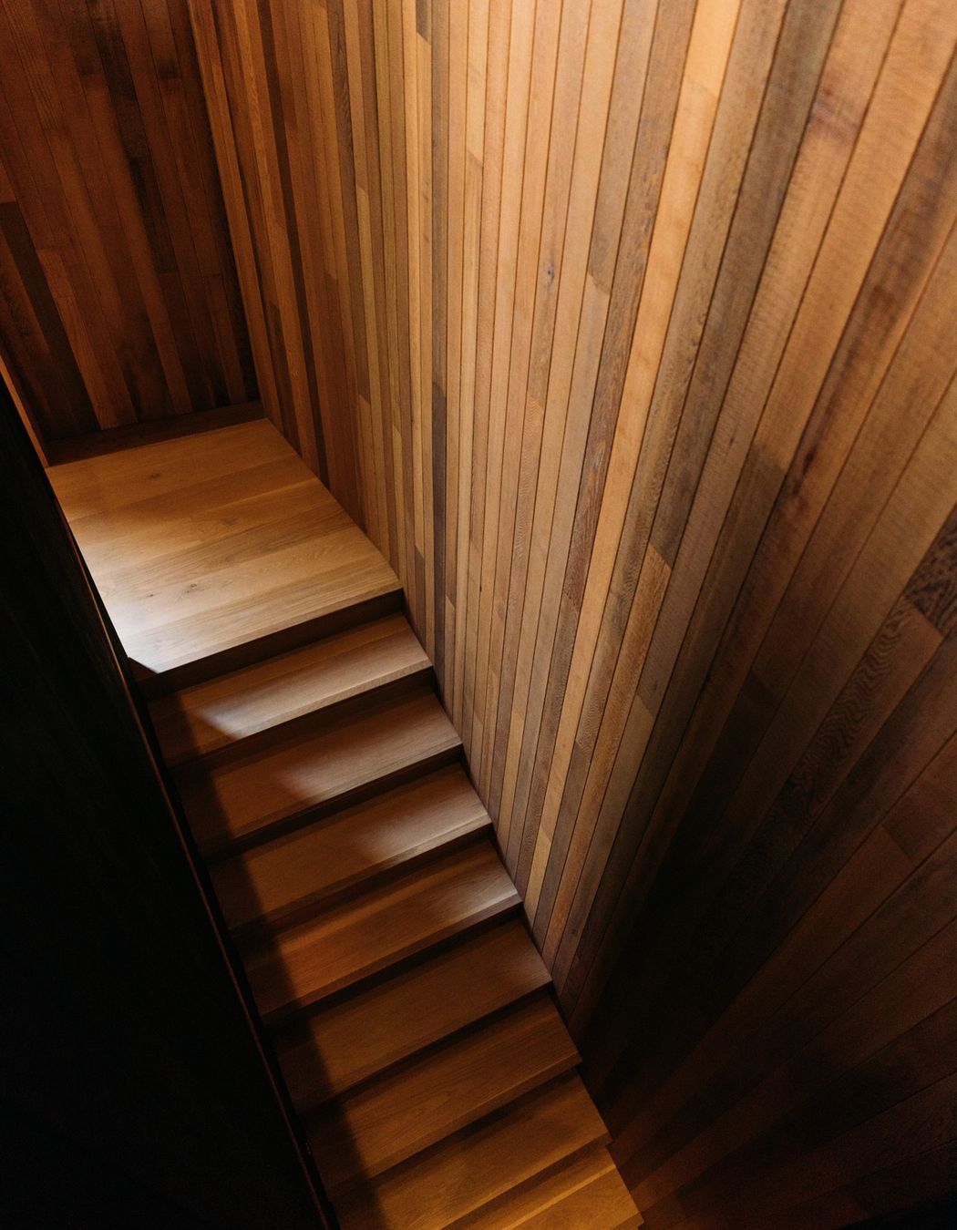 From the top floor living spaces, the staircase leads to the bedrooms and bathrooms located on the lower level.