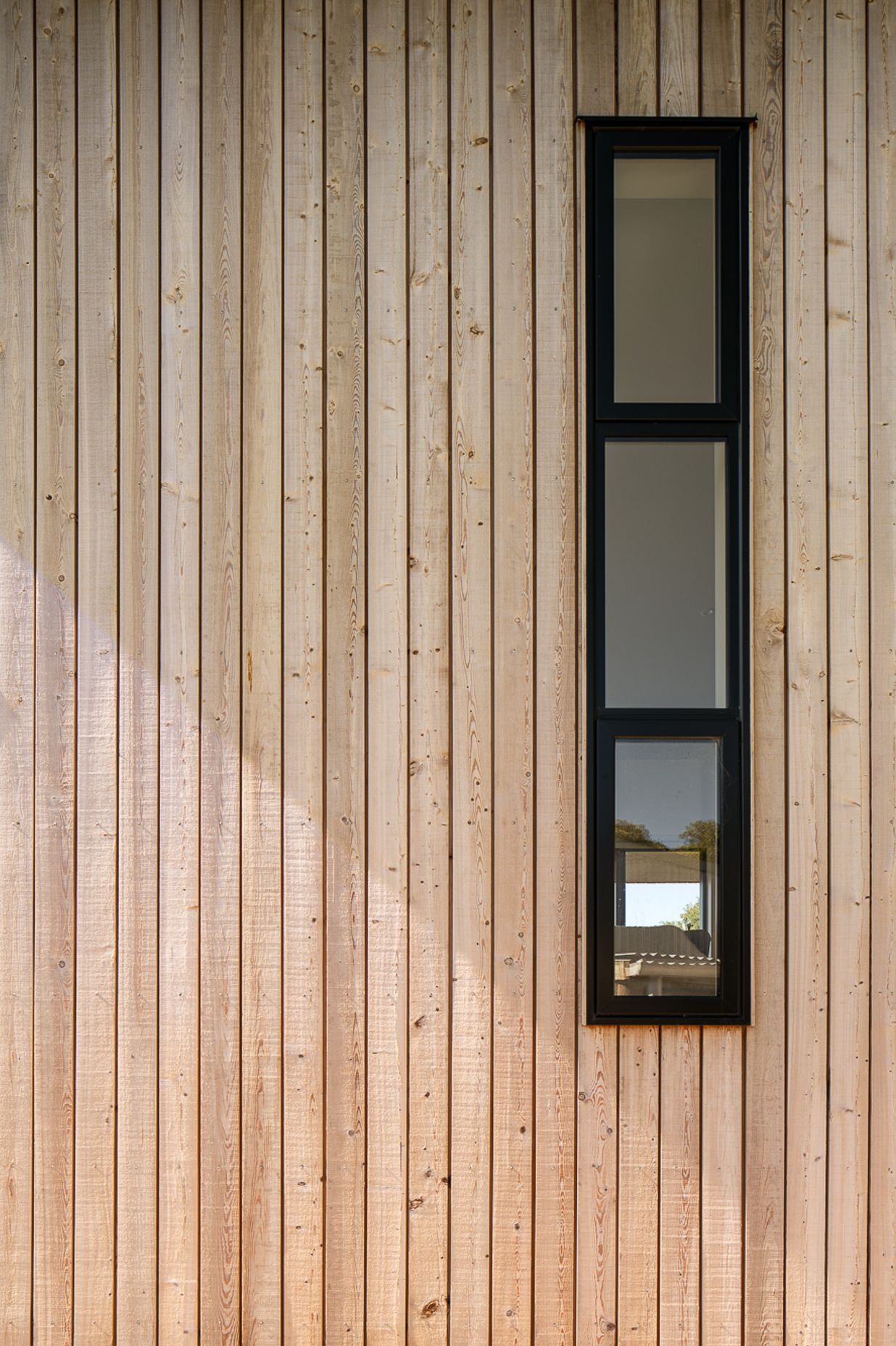 Tall, narrow windows on the western elevation are framed with black joinery.