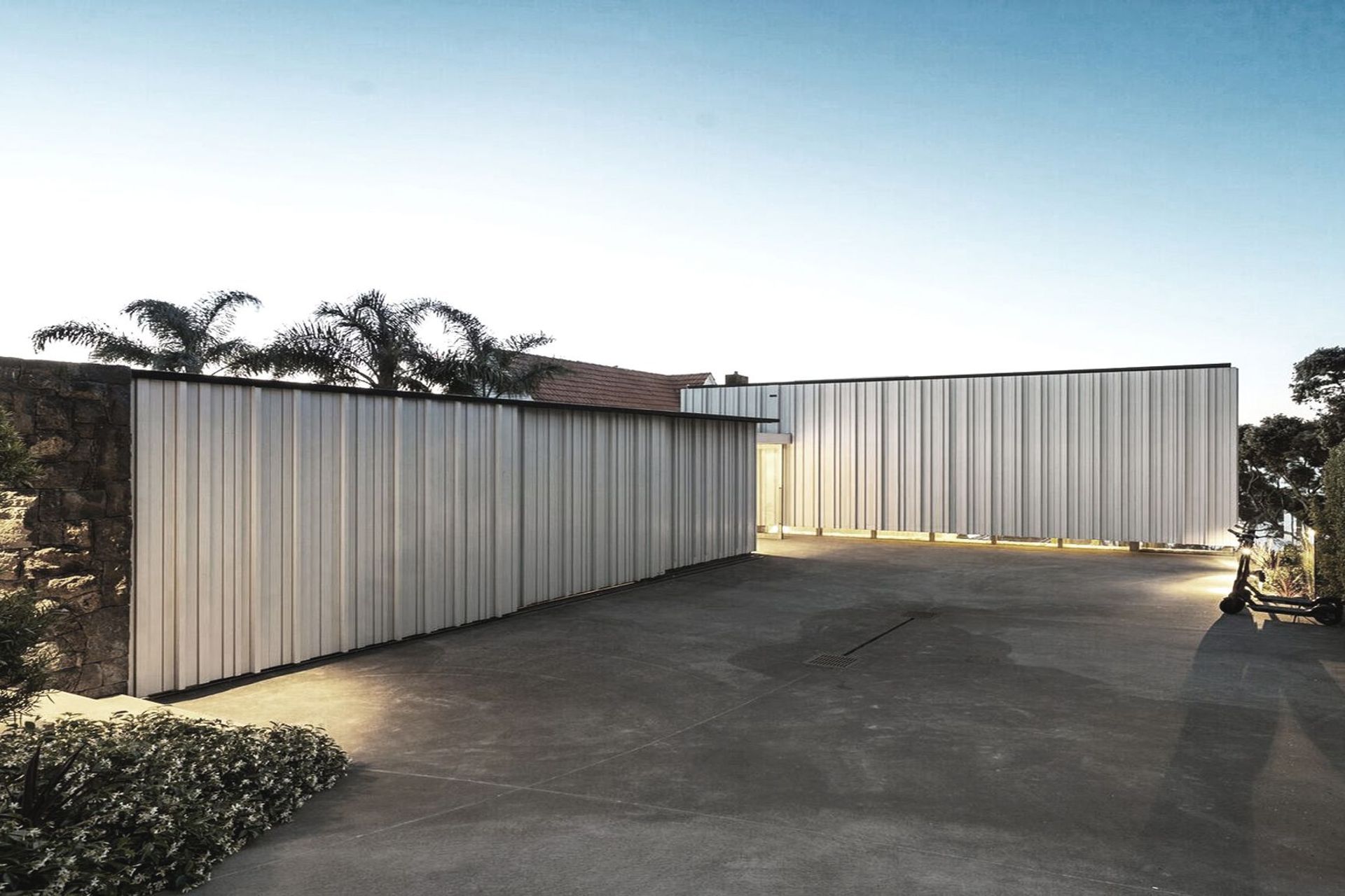 The main entrance is located at the back of the house, which is entered from the road at the top of a steep site. From here, the upper level of the form appears to float, with clerestory windows offering a sneaky peek into the interior of the home.