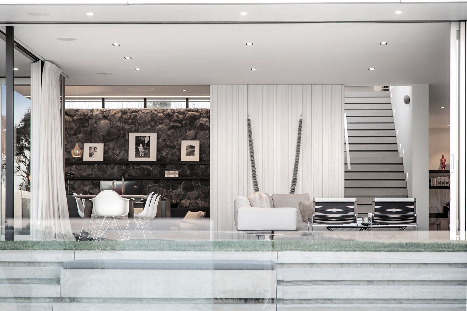 Floating above basalt stone walls are timber-framed pavilions: the top one contains the family spaces and the bottom one contains the living spaces. 