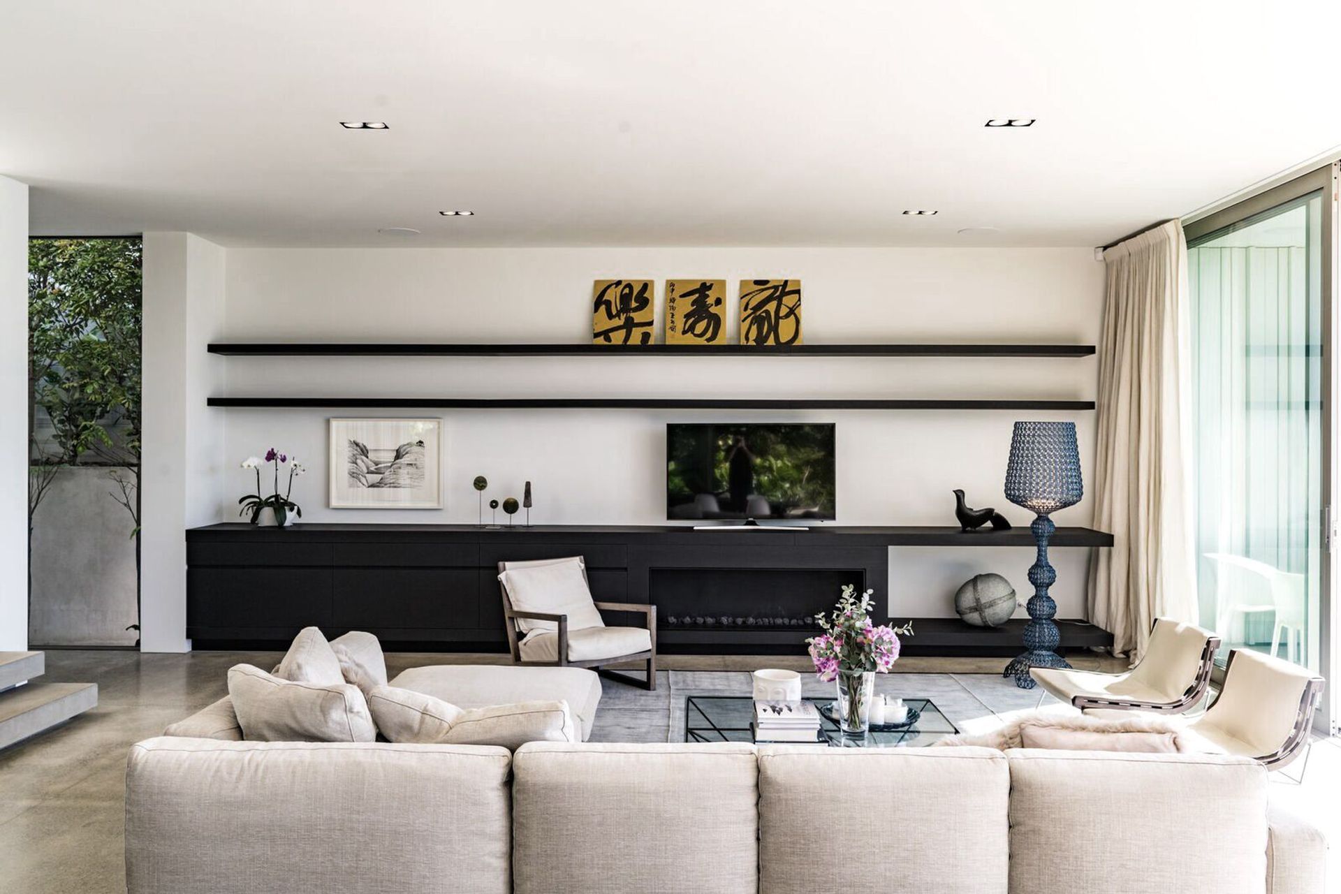 An entire wall of the main living area hosts built-in cabinetry for storage, artworks and media.