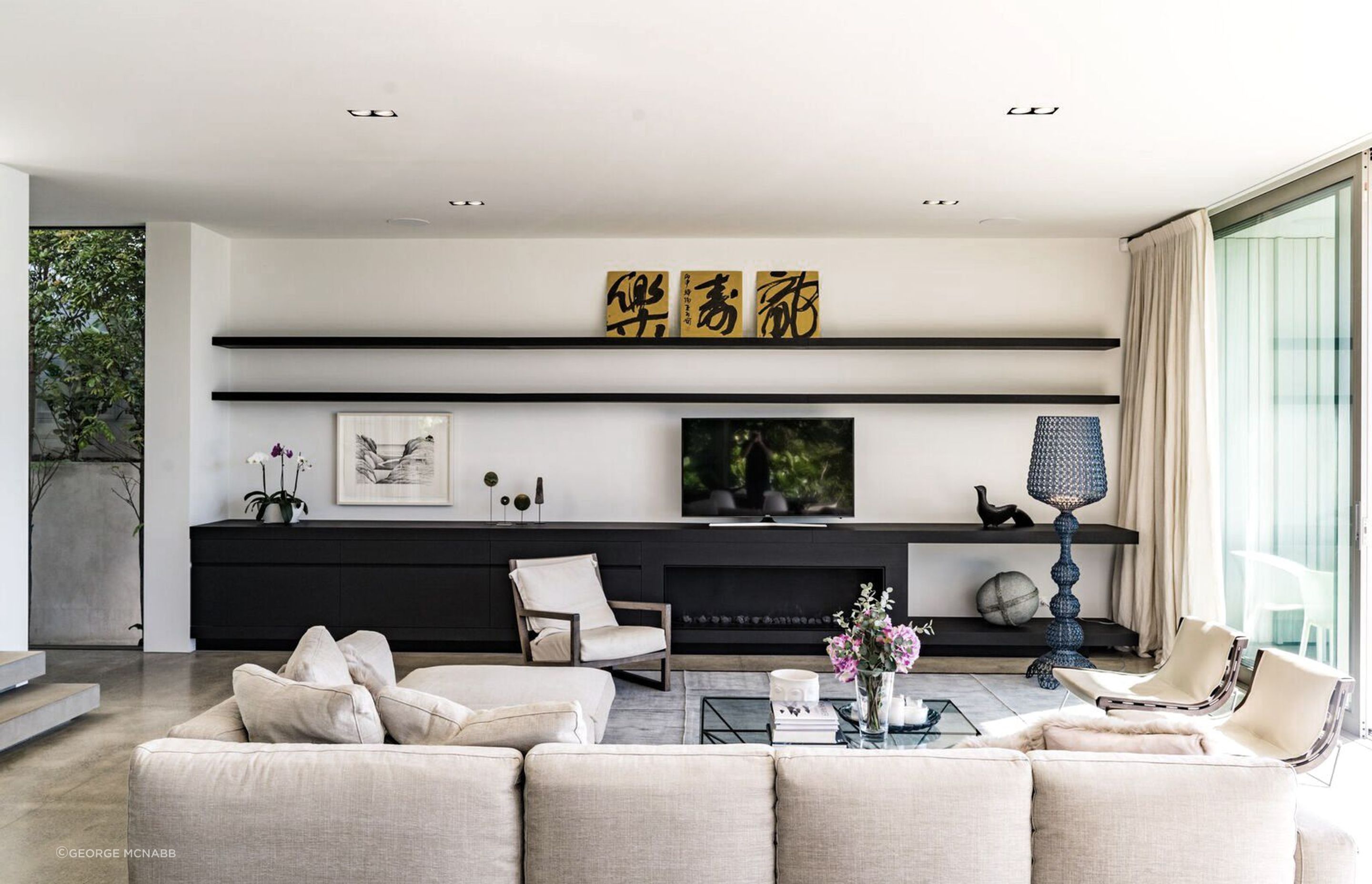 An entire wall of the main living area hosts built-in cabinetry for storage, artworks and media.
