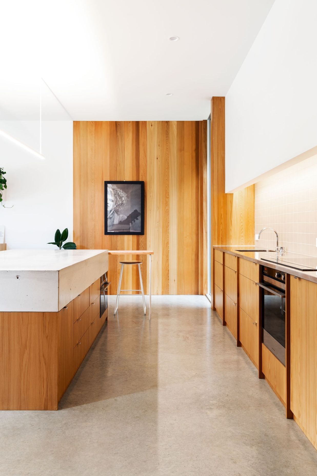 Concrete flooring and timber elements create a restrained palette in the kitchen.