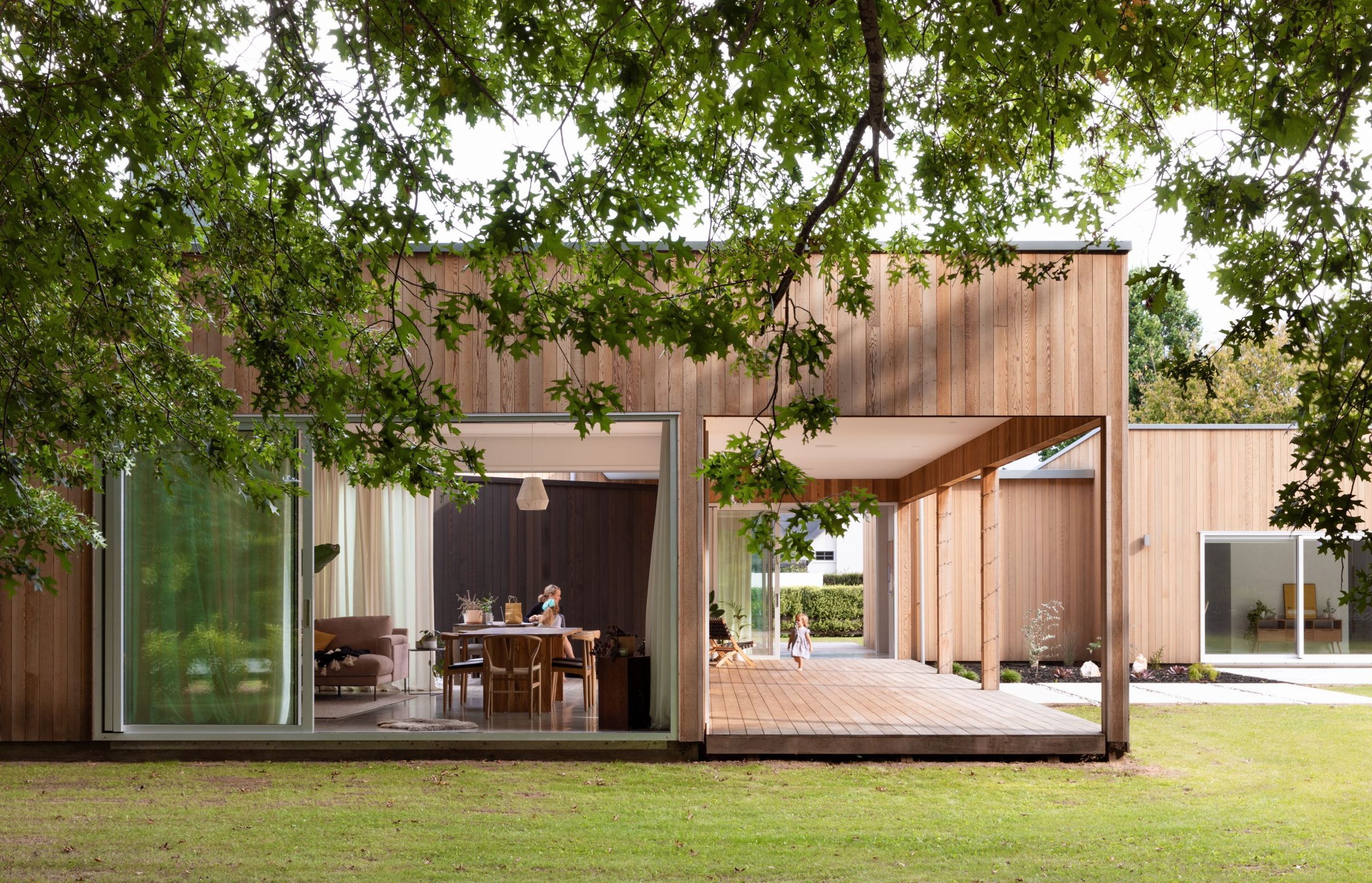 A large verandah extends the living space outside. The house is stripped of adornment and presents a strong, minimal composition.
