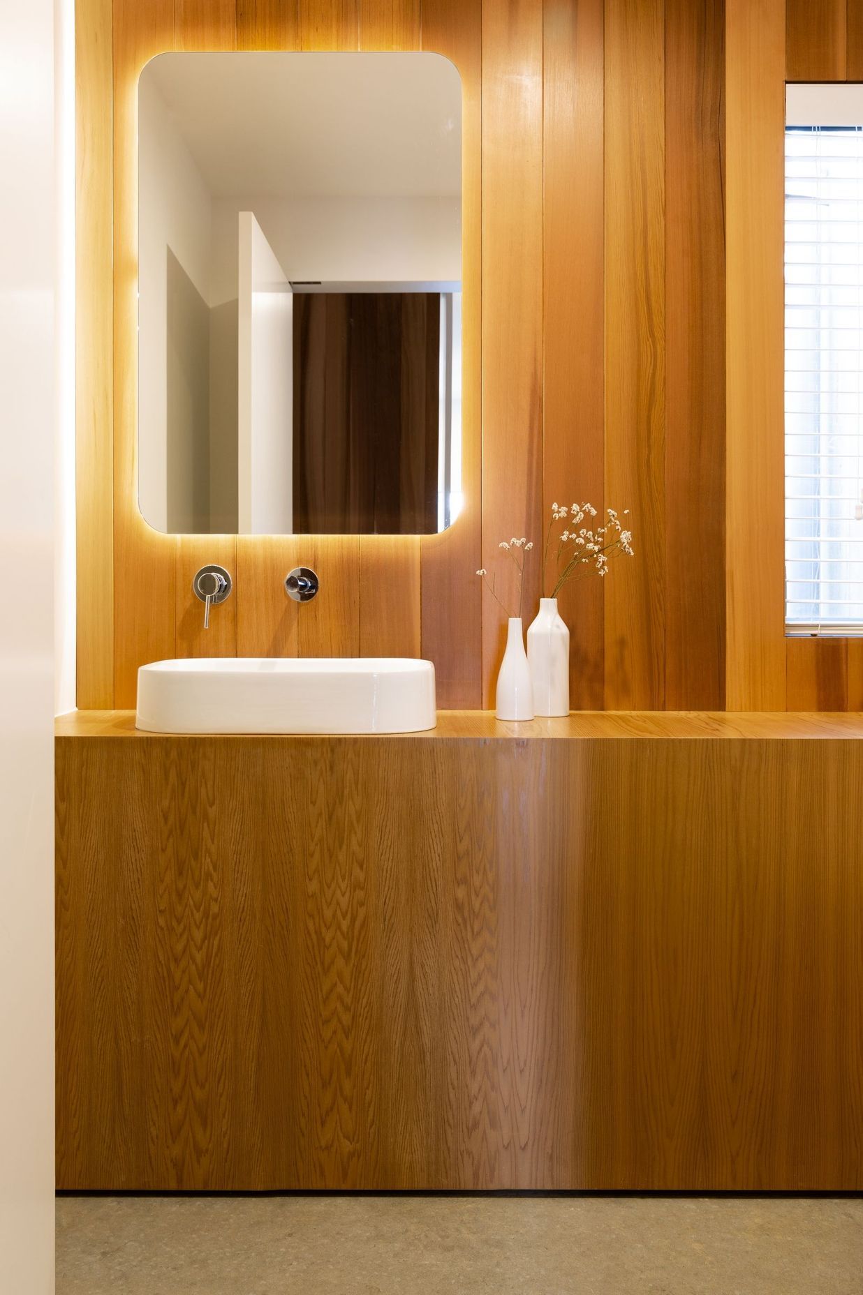 A wall of built-in timber cabinetry and panelling creates a graceful bathroom.