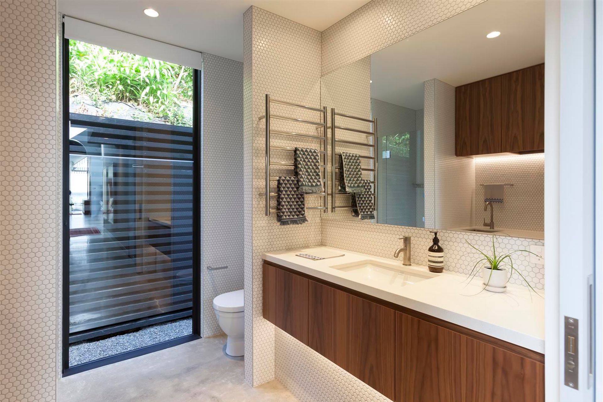 The bathroom is a contemporary take on the traditional dichromatic colour scheme using white hexagonal mosaics and walnut timber.