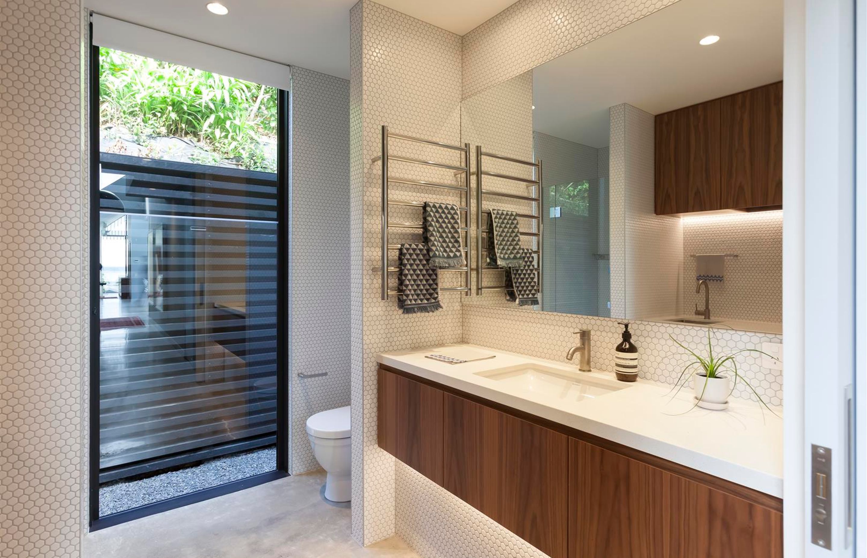 The bathroom is a contemporary take on the traditional dichromatic colour scheme using white hexagonal mosaics and walnut timber.