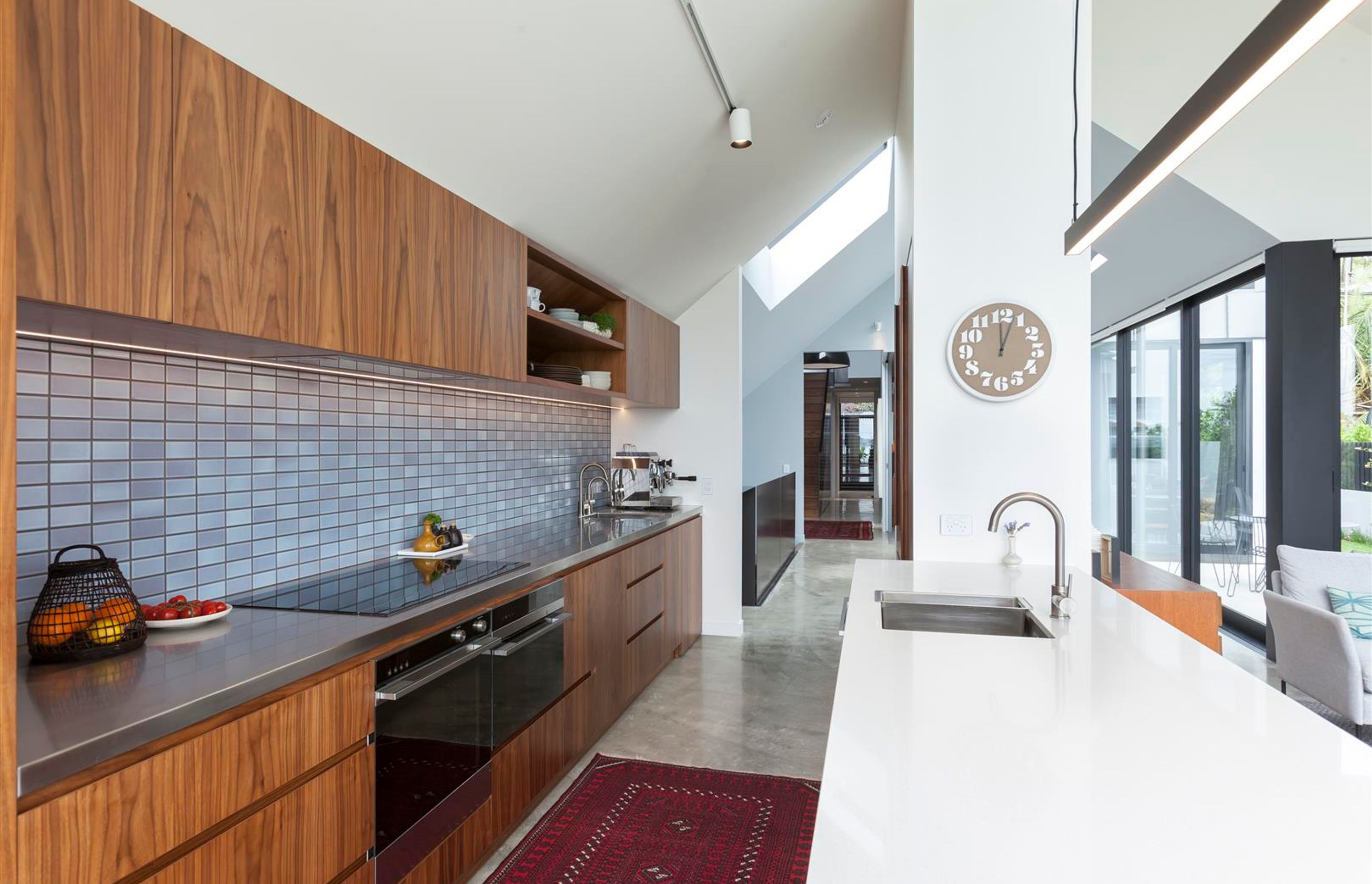 The internal material palette has been pared back, as per the client's wishes, to incorporate polished concrete, walnut timber and steel plate, offset by crisp white and muted tones.