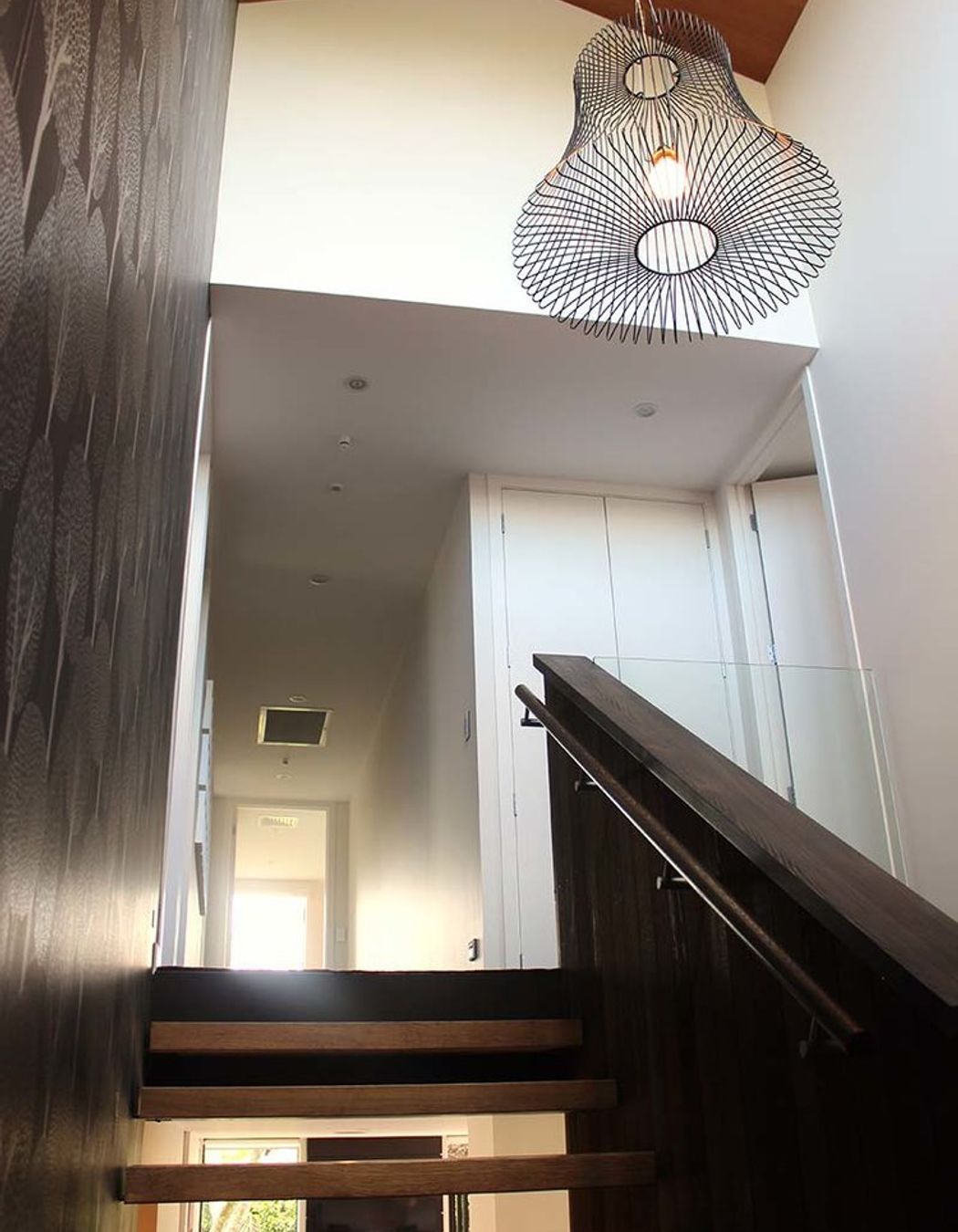 Open riser stairs let light from the entry void further penetrate all levels of the house.