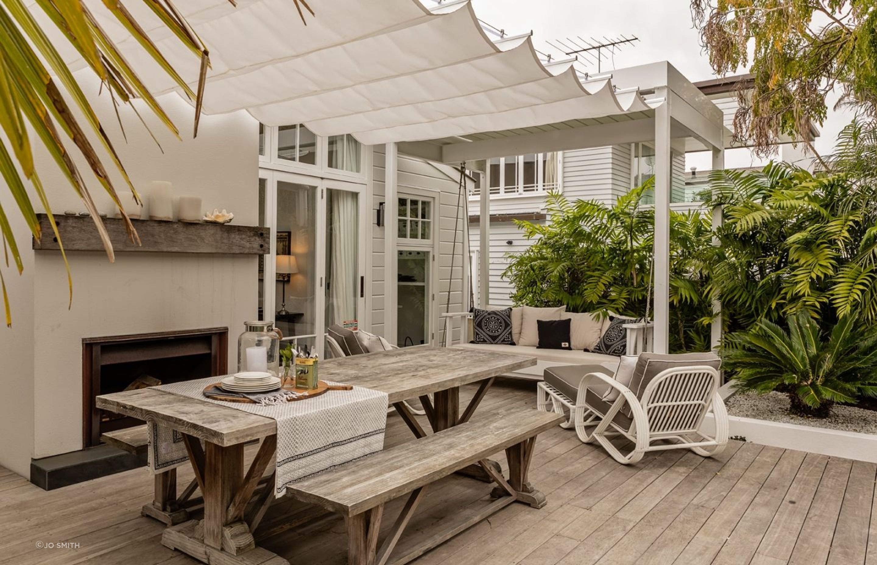 A decked outdoor room with fireplace on the rear of the home.