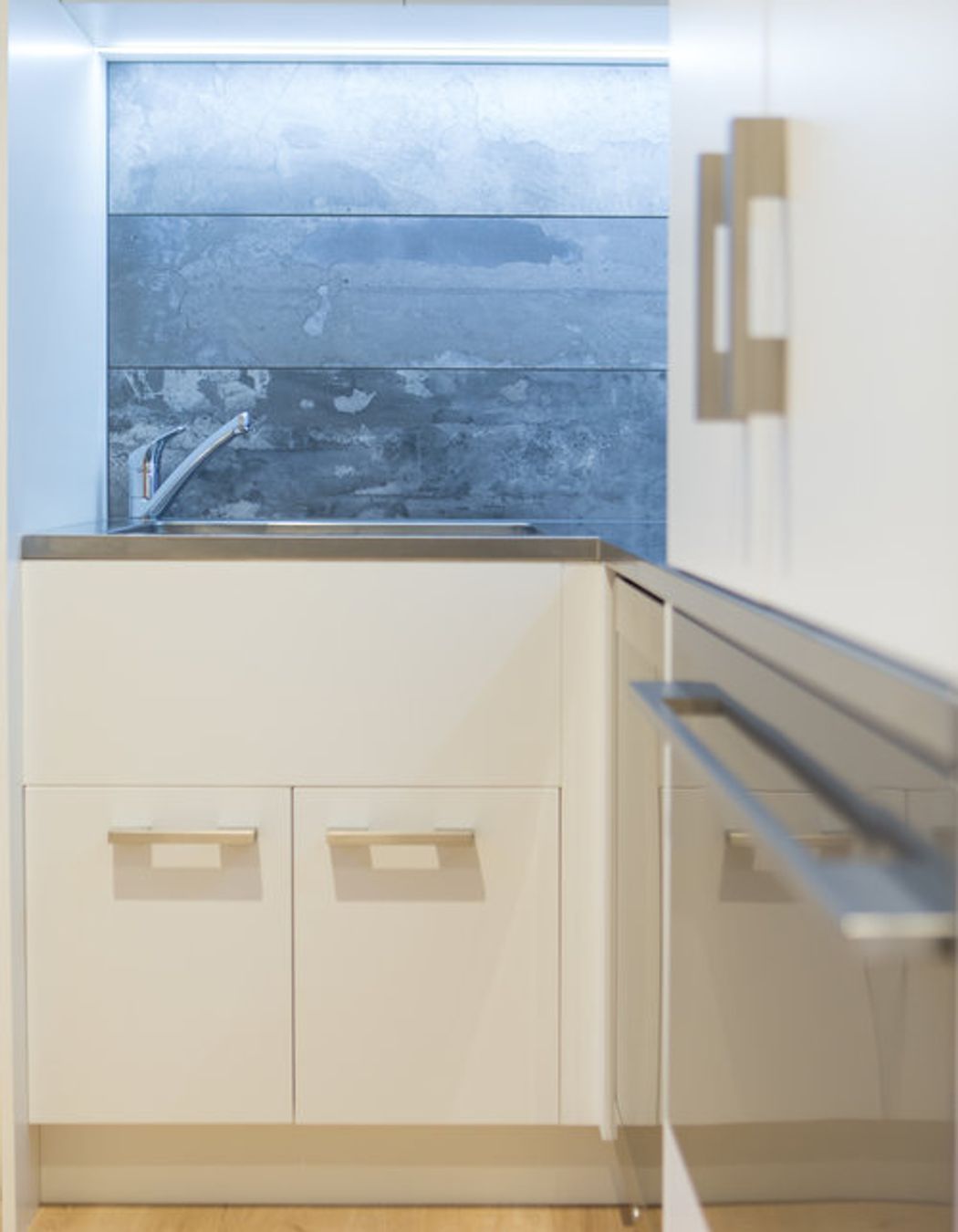 Strong stone splashback is paired with a deep stainless laundry sink.