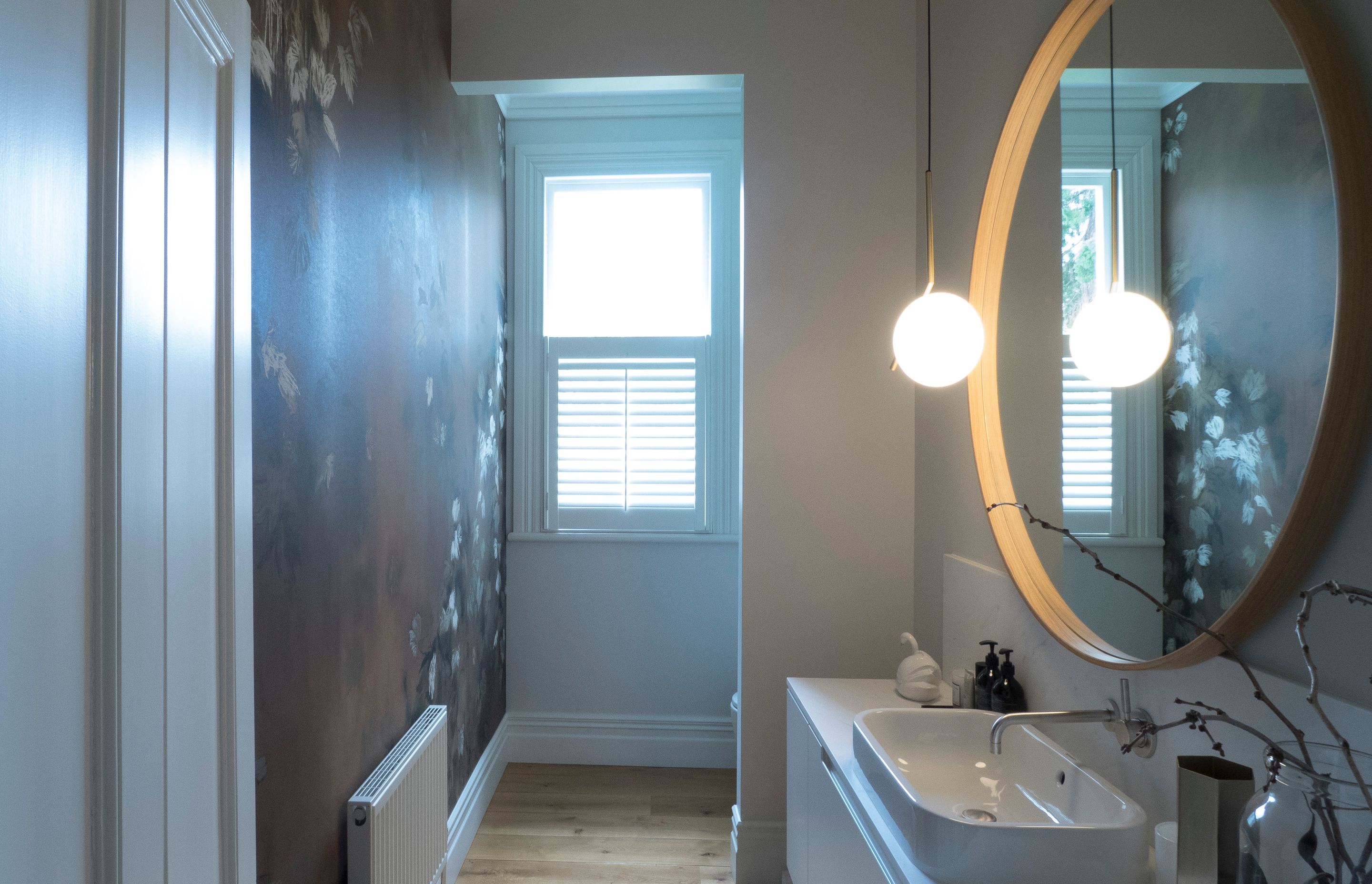 Guest Bathroom featuring stunning wallpaper reflected in mirror.