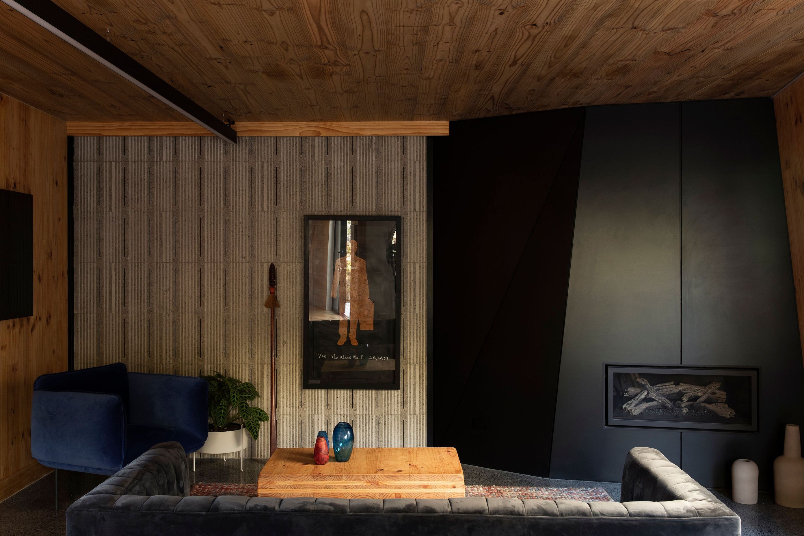 The lounge area has two feature walls, one faceted wall hosts the fireplace, while the concrete wall has a textural impression created by polystyrene formwork.