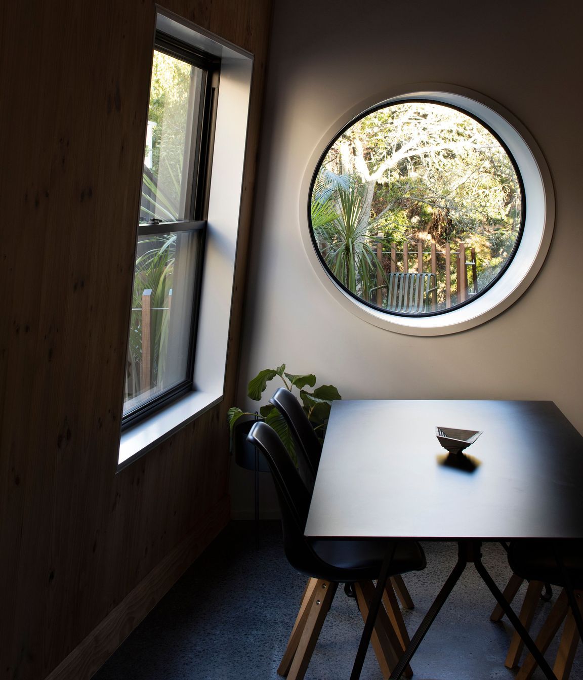A port hole in the dining area looks out over the deck to the plum tree.