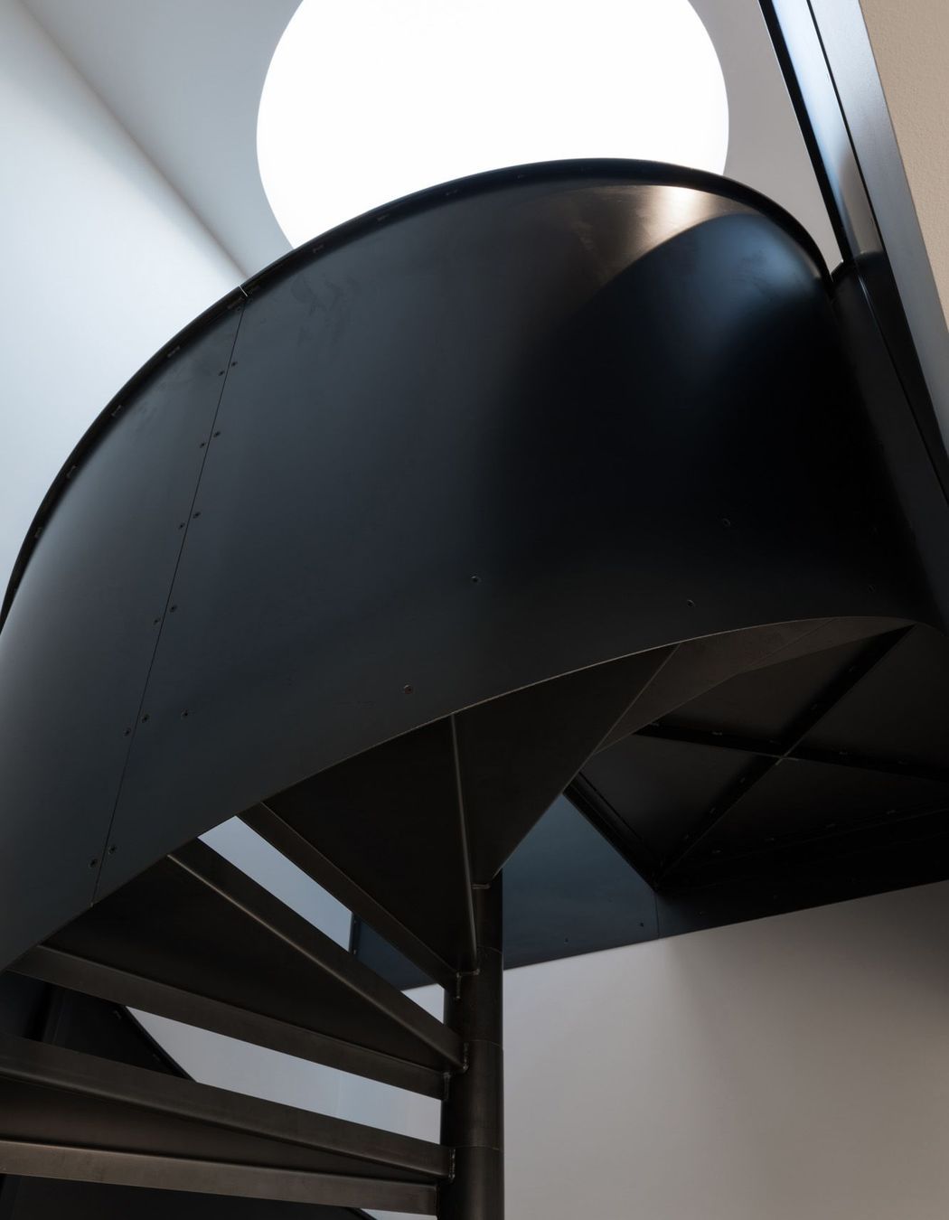 A black spiral staircase made in steel plate is a key architectural feature.