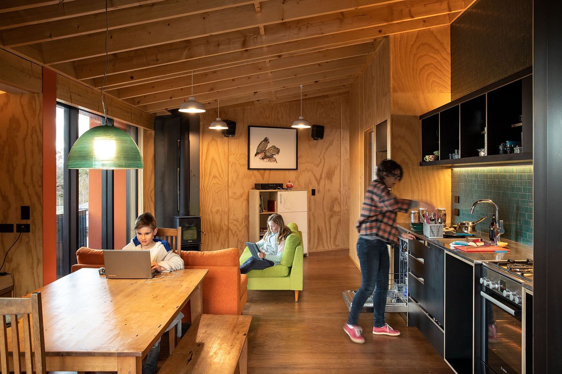 New Zealand pine plywood creates a warm and inviting kitchen and dining area. The galley-style kitchen features open shelving like you'd find in a DOC tramping hut.