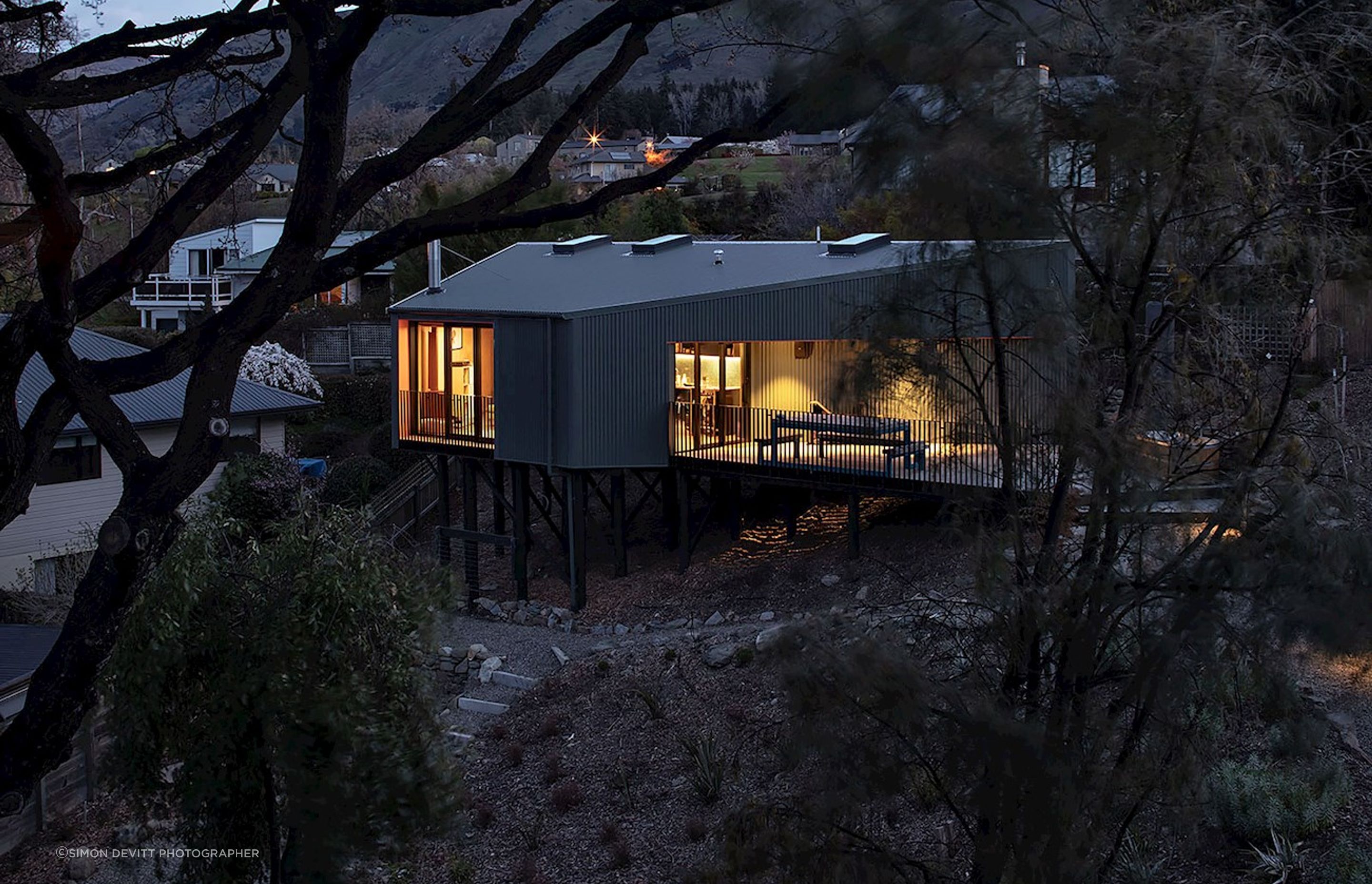 On a very steep site in Wanaka, this modest holiday home is elevated up on poles, like a kea bird perched in the trees.