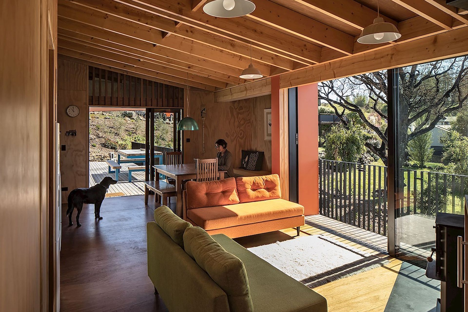 The living area is lit by huge sliding doors that leads onto a small decked area. The owners had bespoke sofas made to match the green and orange on the exterior.