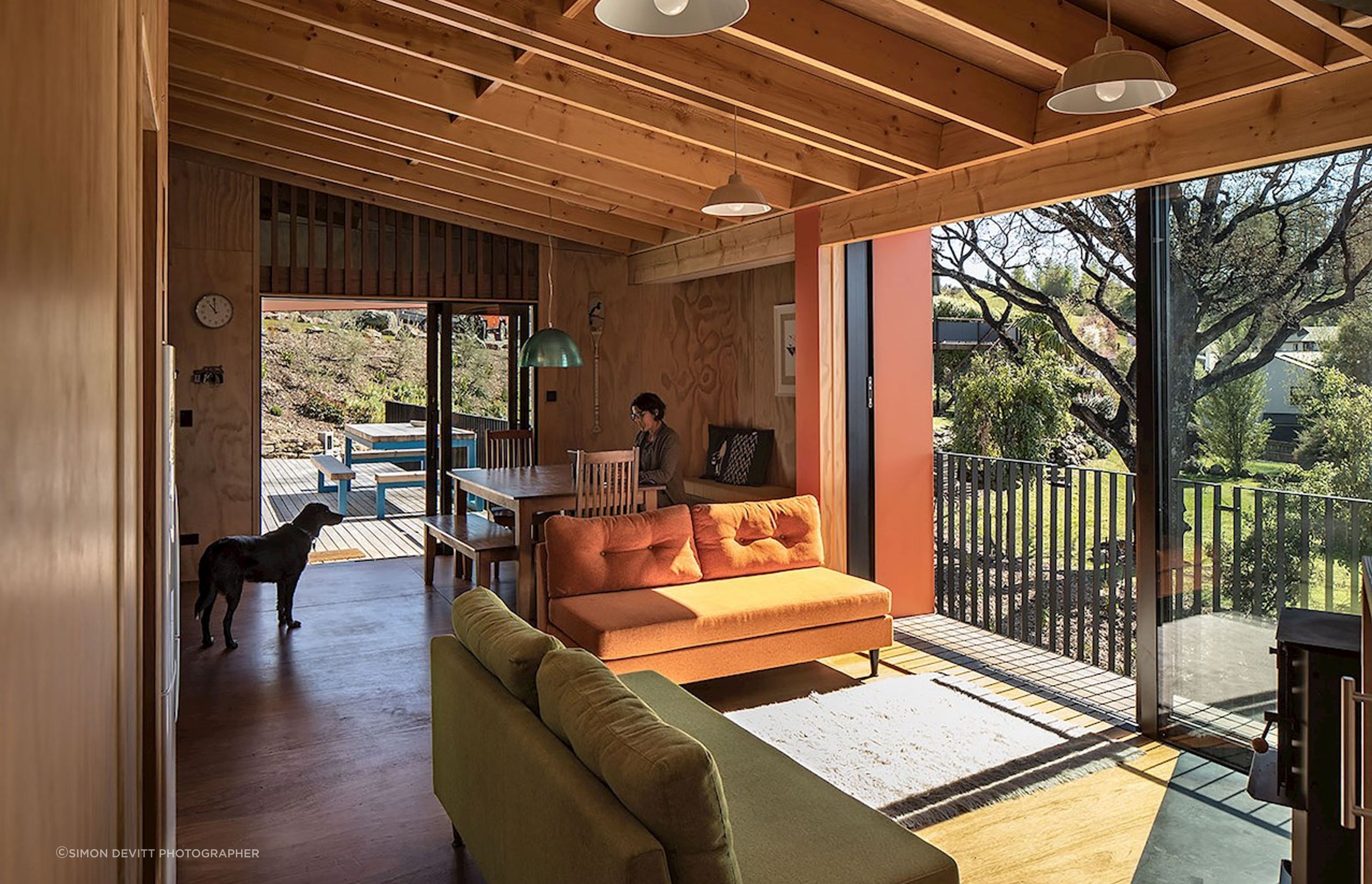 The living area is lit by huge sliding doors that leads onto a small decked area. The owners had bespoke sofas made to match the green and orange on the exterior.