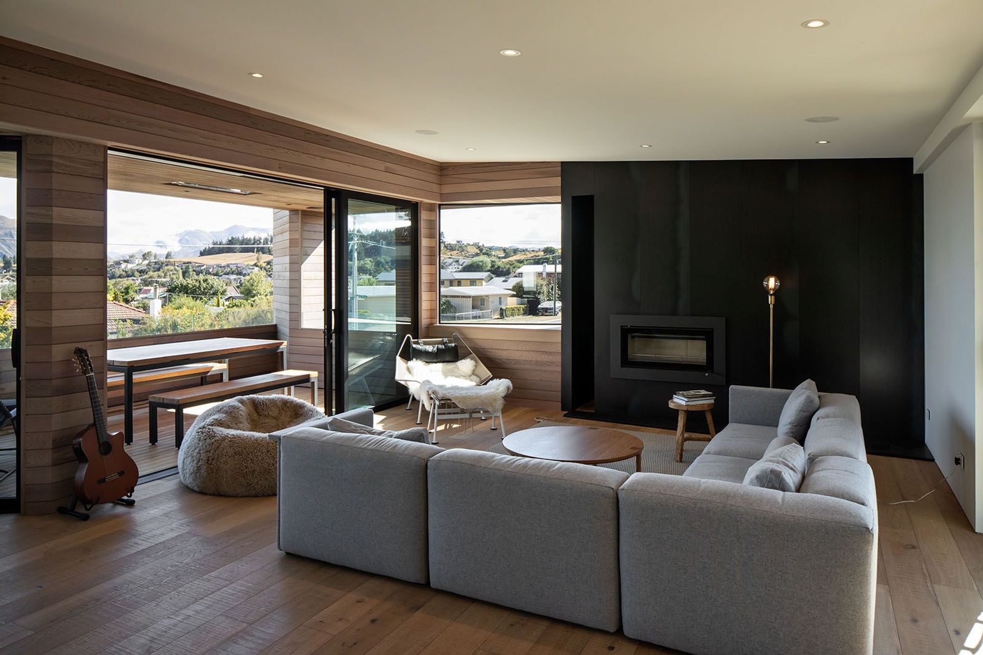 The open-plan living space opens via the balcony to the view. A steel feature wall incorporates a fireplace. The timber-panelled floor and  front wall flows through to the balcony.