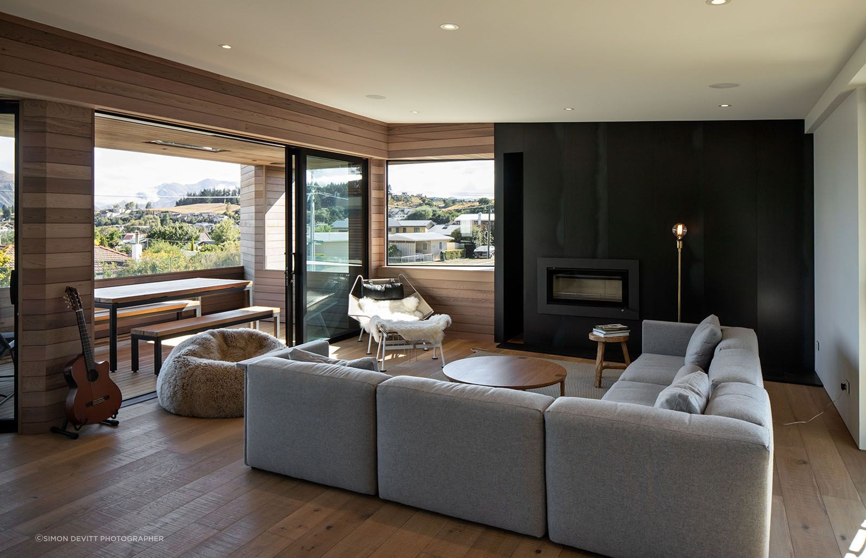 The open-plan living space opens via the balcony to the view. A steel feature wall incorporates a fireplace. The timber-panelled floor and front wall flows through to the balcony.