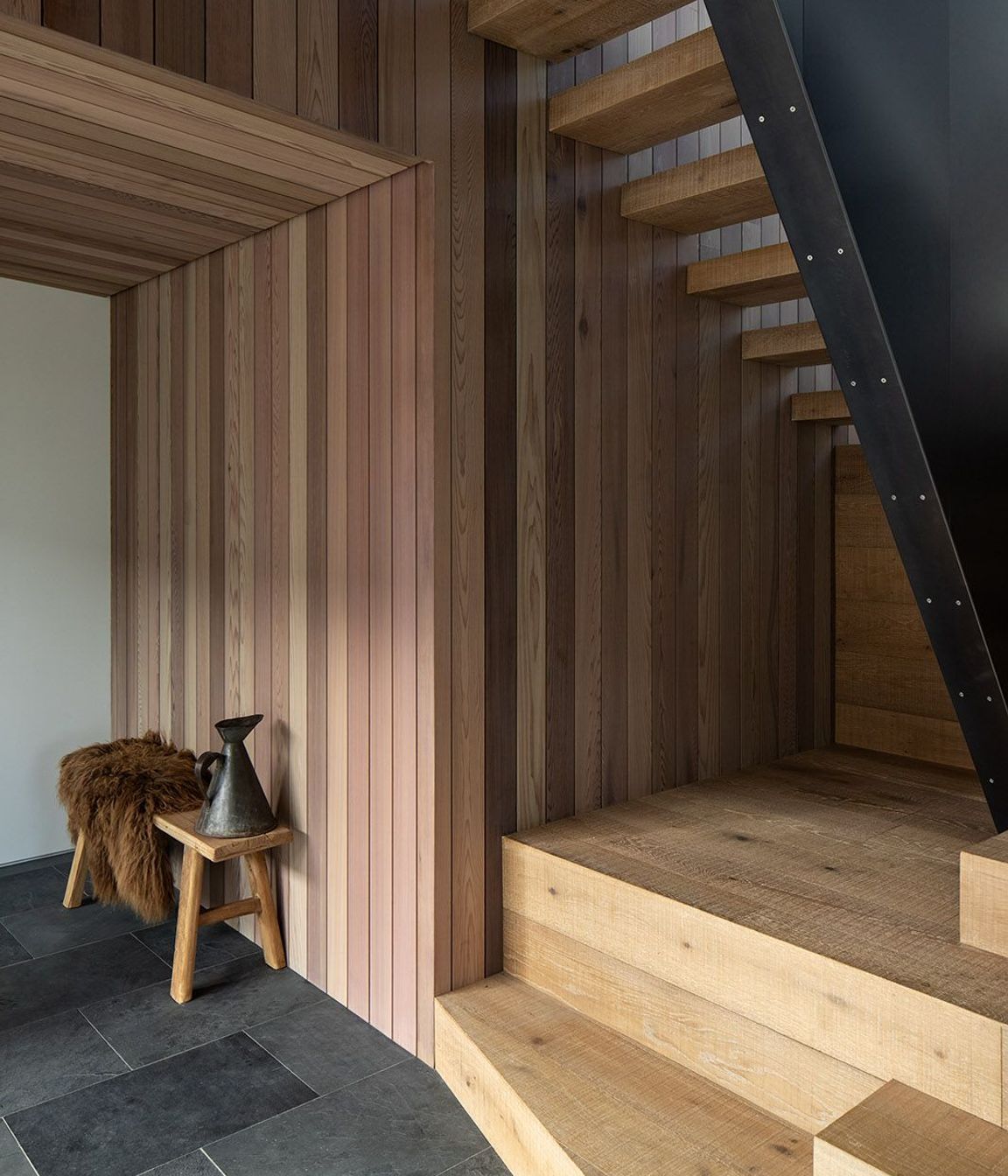 Slate tiles and a steel ballastrade provide a strong contrast to the warm timber on the staircase.