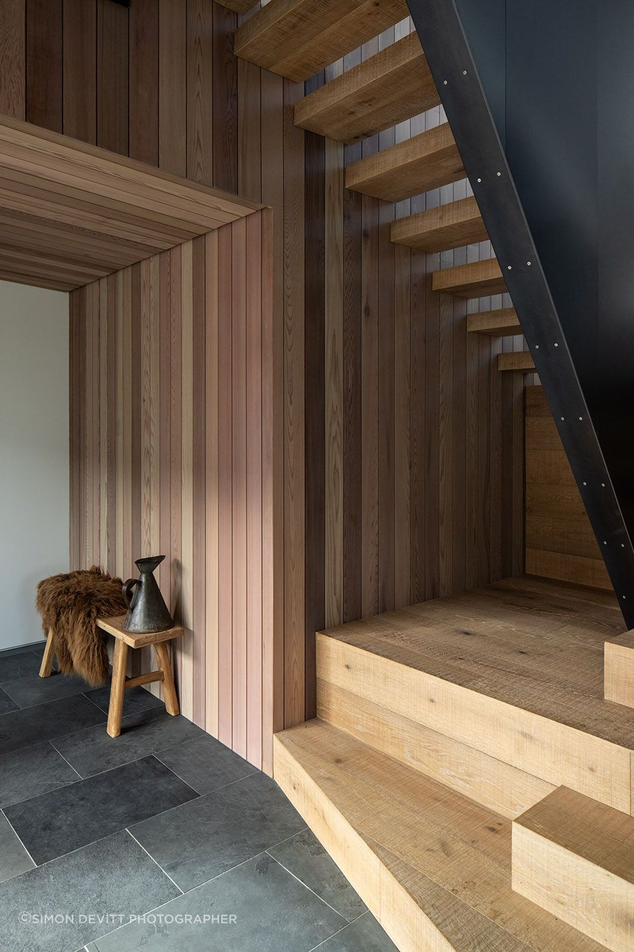 Slate tiles and a steel ballastrade provide a strong contrast to the warm timber on the staircase.