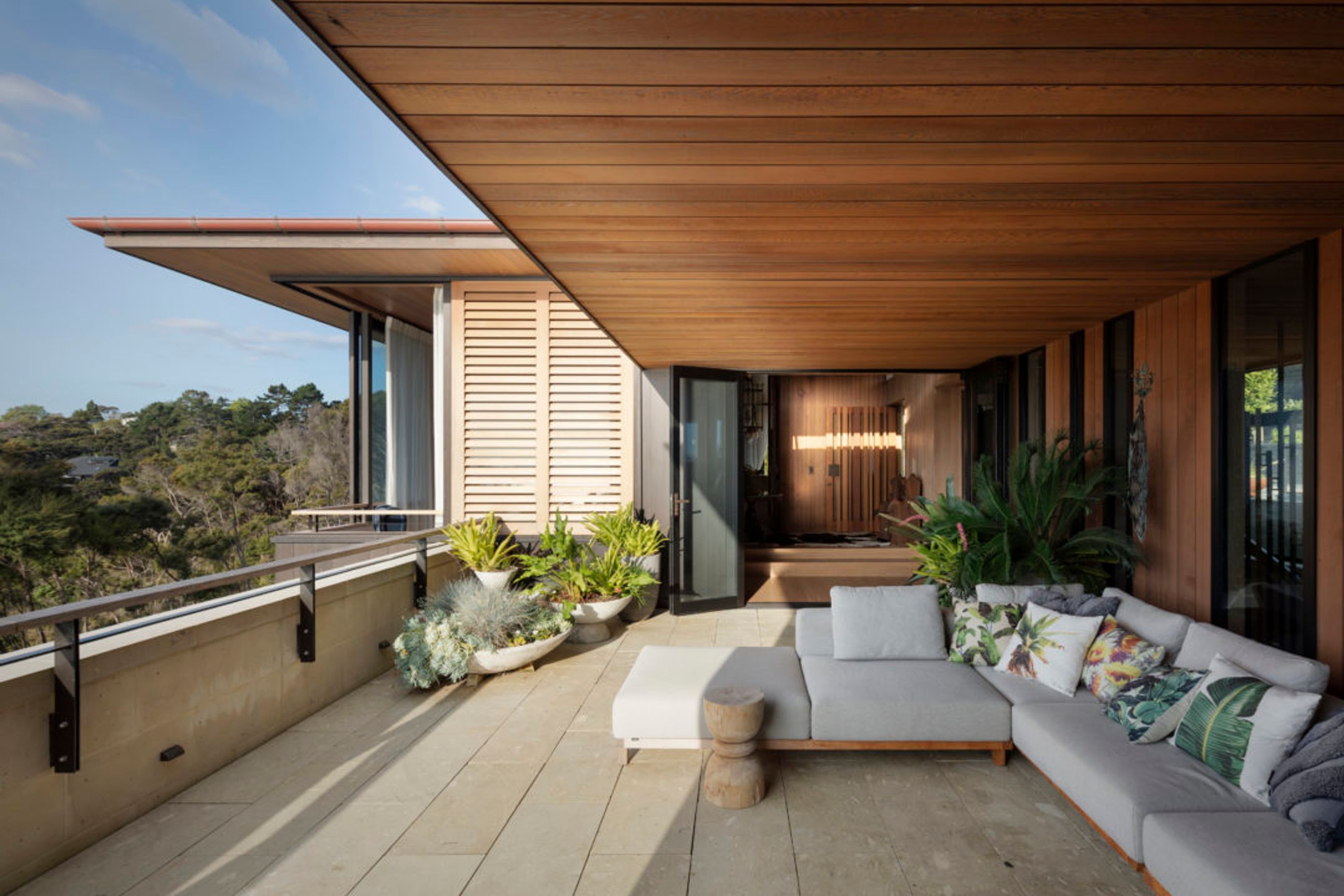 The terrace on the upper floor creates an outdoor room with views to the sea, sheltered by a cedar soffit.