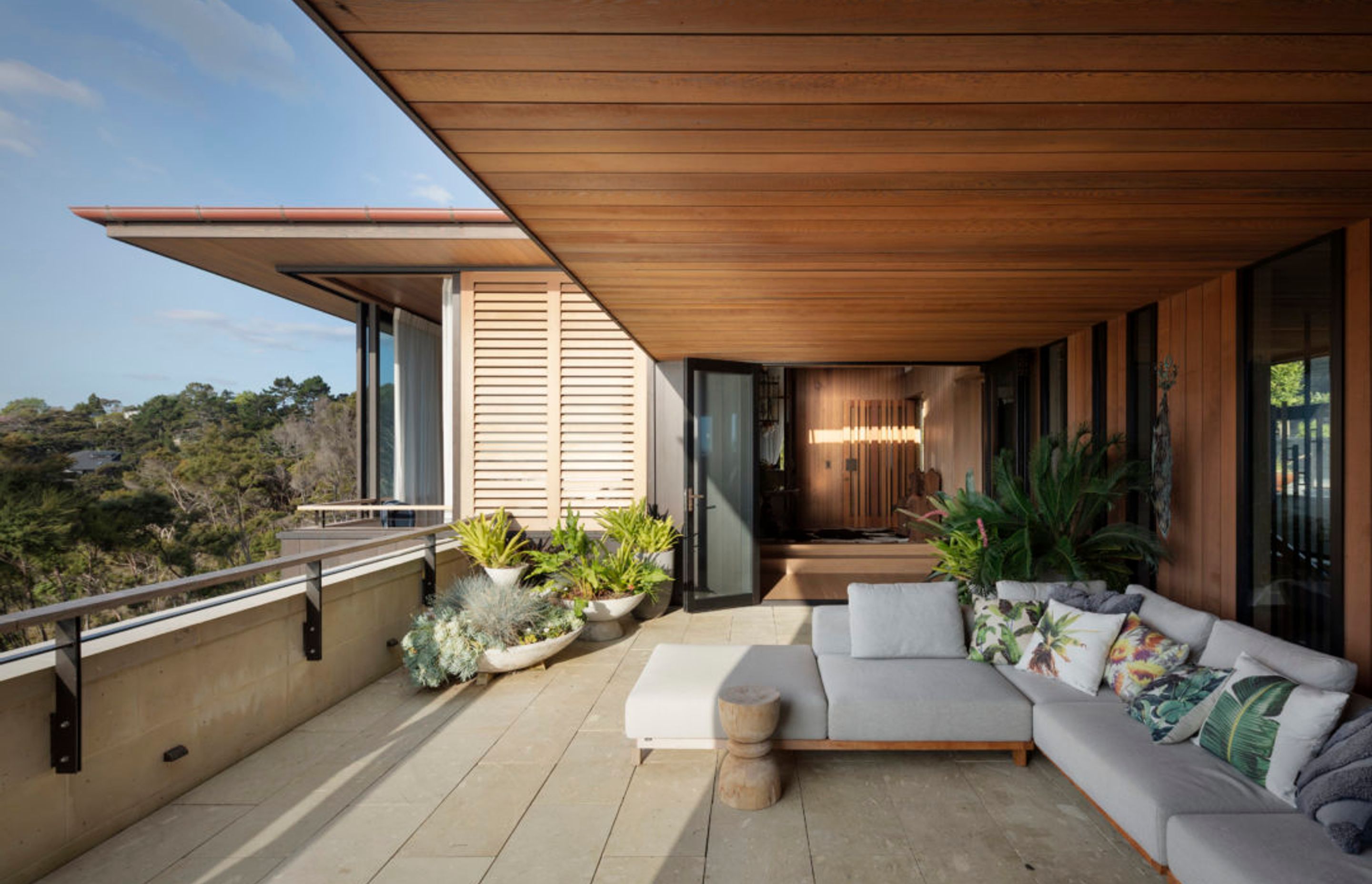 The terrace on the upper floor creates an outdoor room with views to the sea, sheltered by a cedar soffit.
