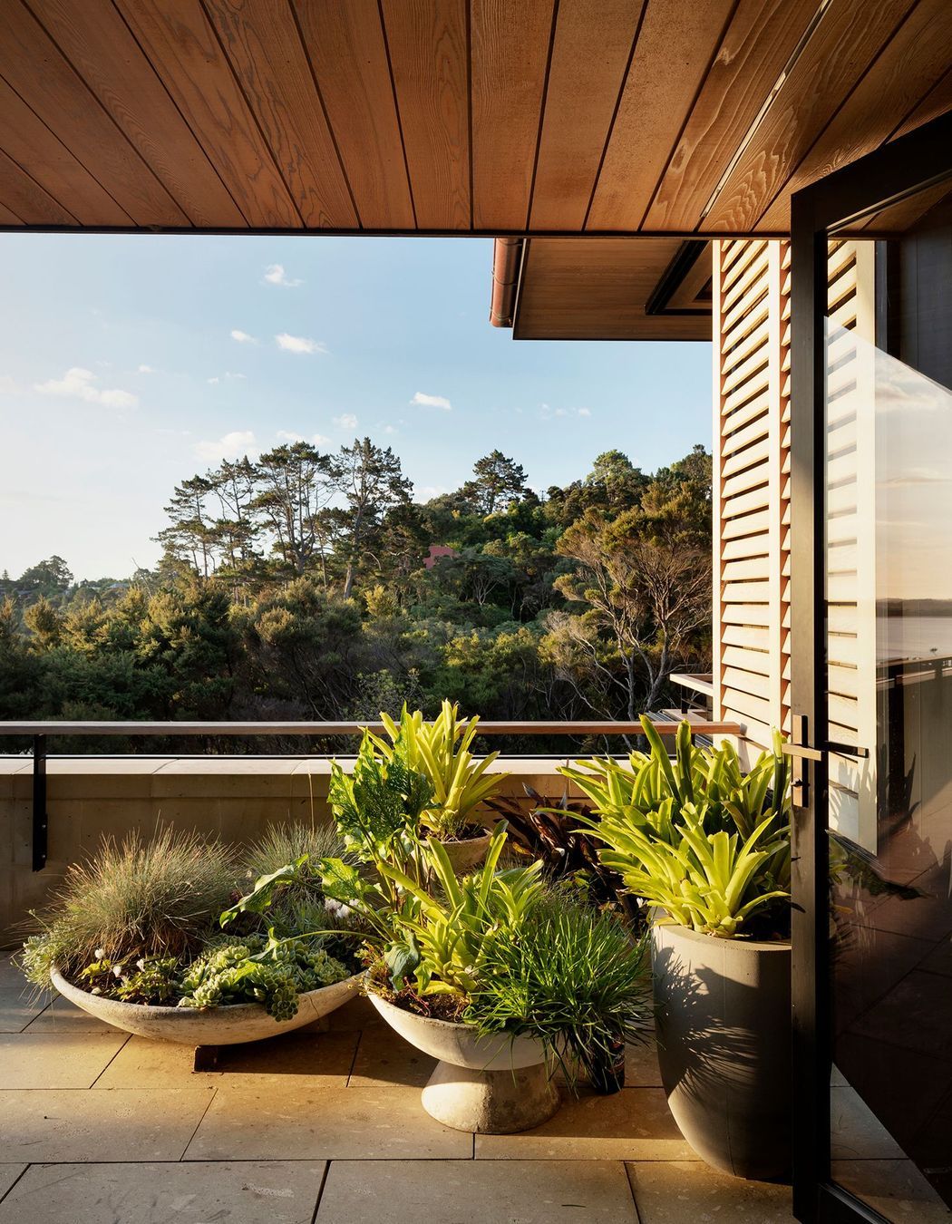 Potted plants blend the terrace in with the view of rejuvenating bush.