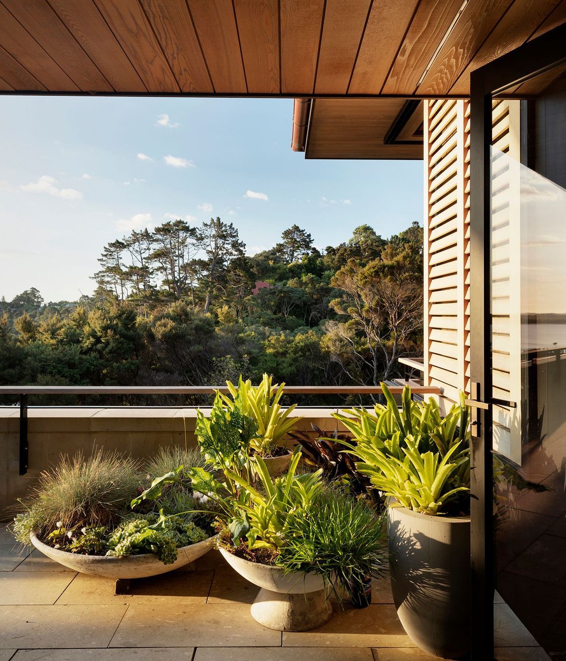 Potted plants blend the terrace in with the view of rejuvenating bush.