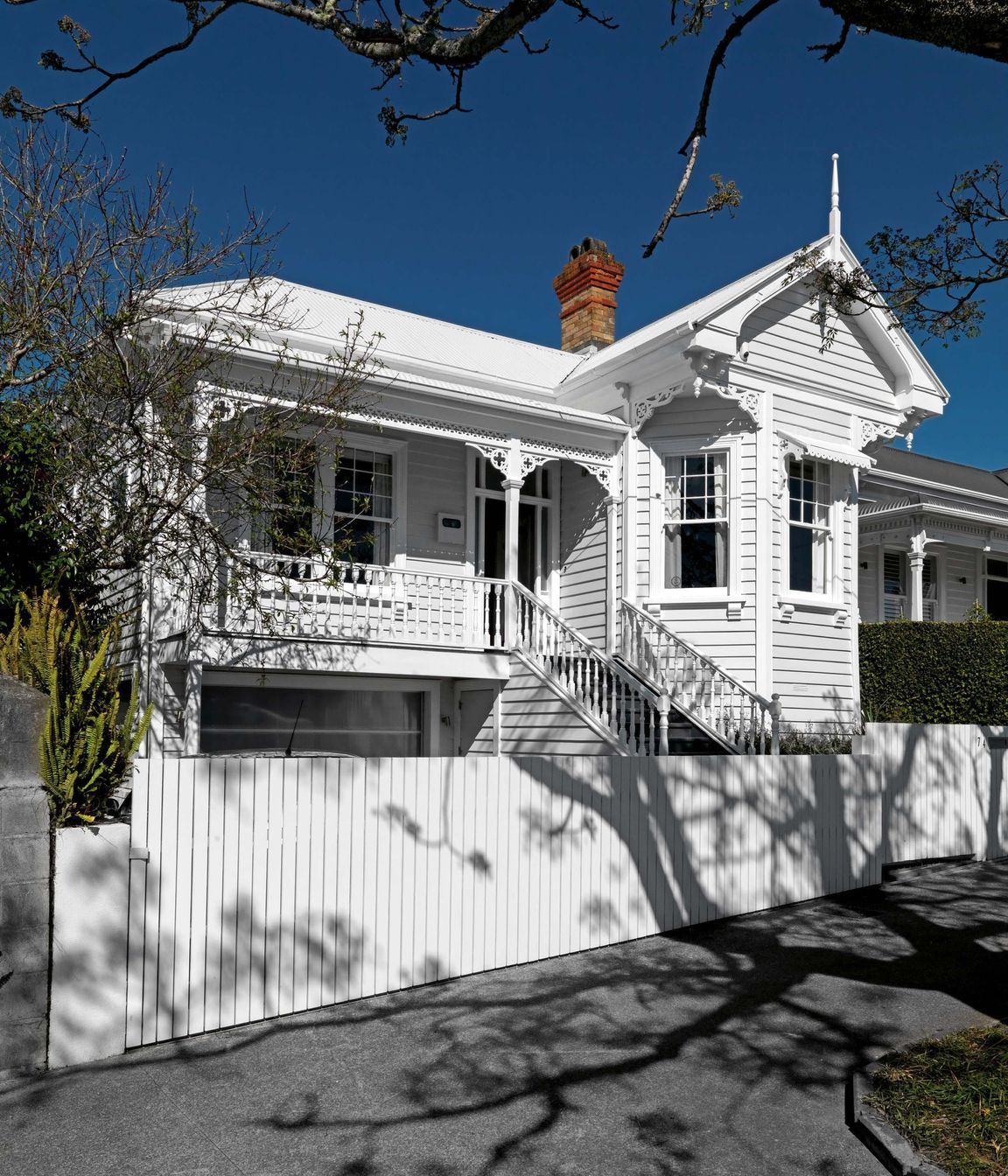 The front elevation is a classic Ponsonby villa with a bay window and verandah – looking fresh and crisp painted all in white.