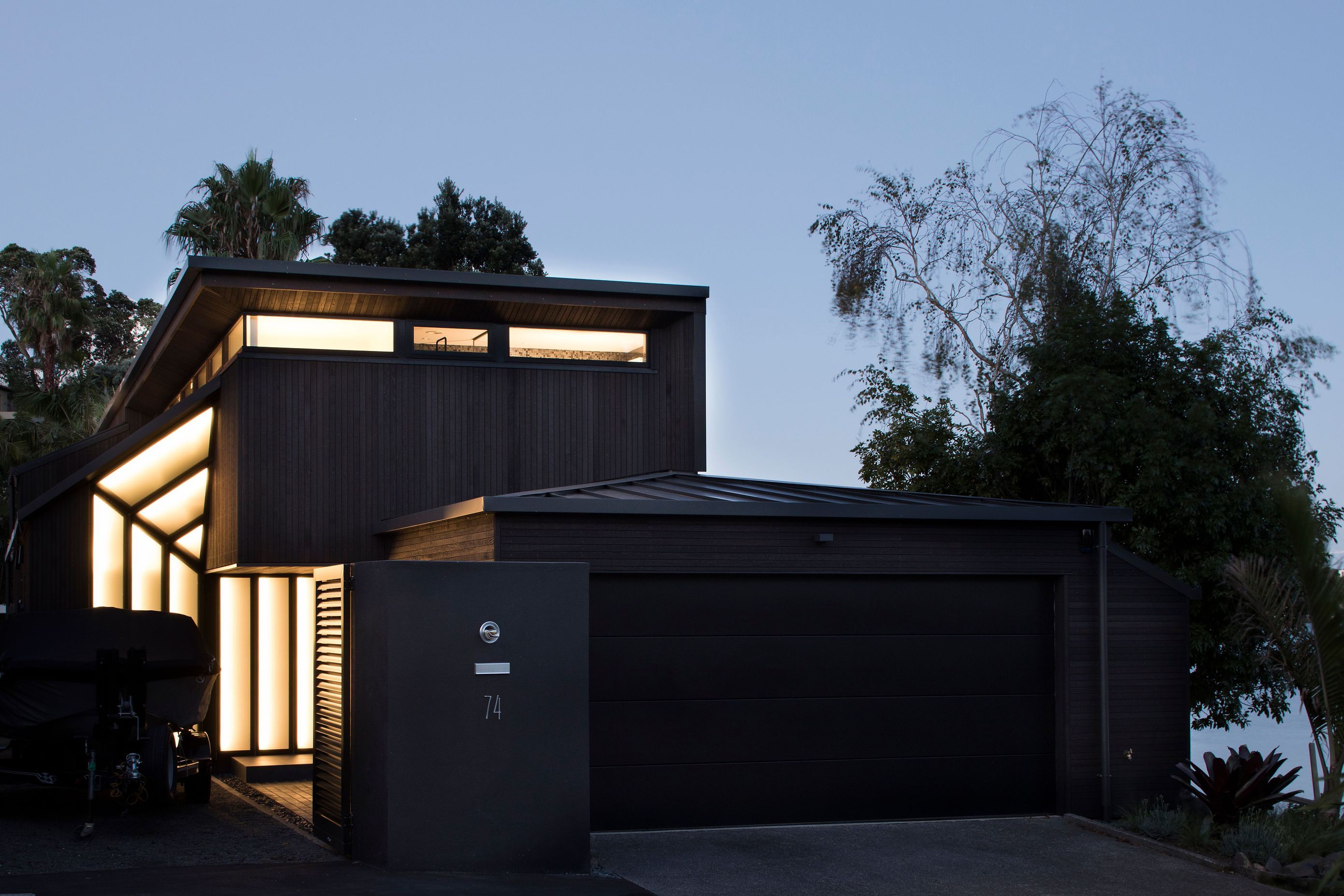 With a prominent garage out front, seen from the street at night, a new entrance offers a warm and welcoming navigational cue to visitors. The street elevation shows the existing building with it's new dark-stained cedar cladding, aluminium roofing and en