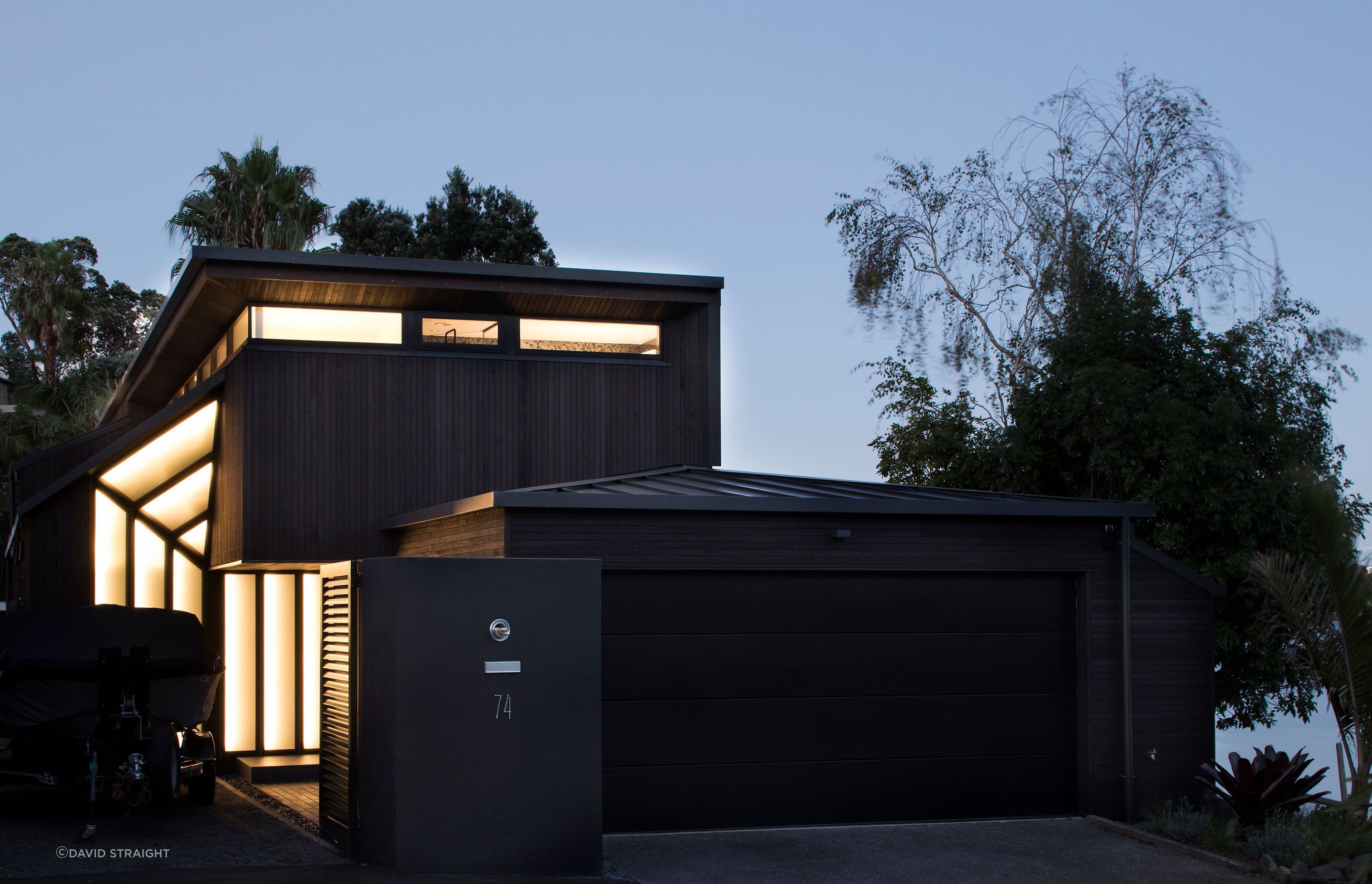 With a prominent garage out front, seen from the street at night, a new entrance offers a warm and welcoming navigational cue to visitors. The street elevation shows the existing building with it's new dark-stained cedar cladding, aluminium roofing and en