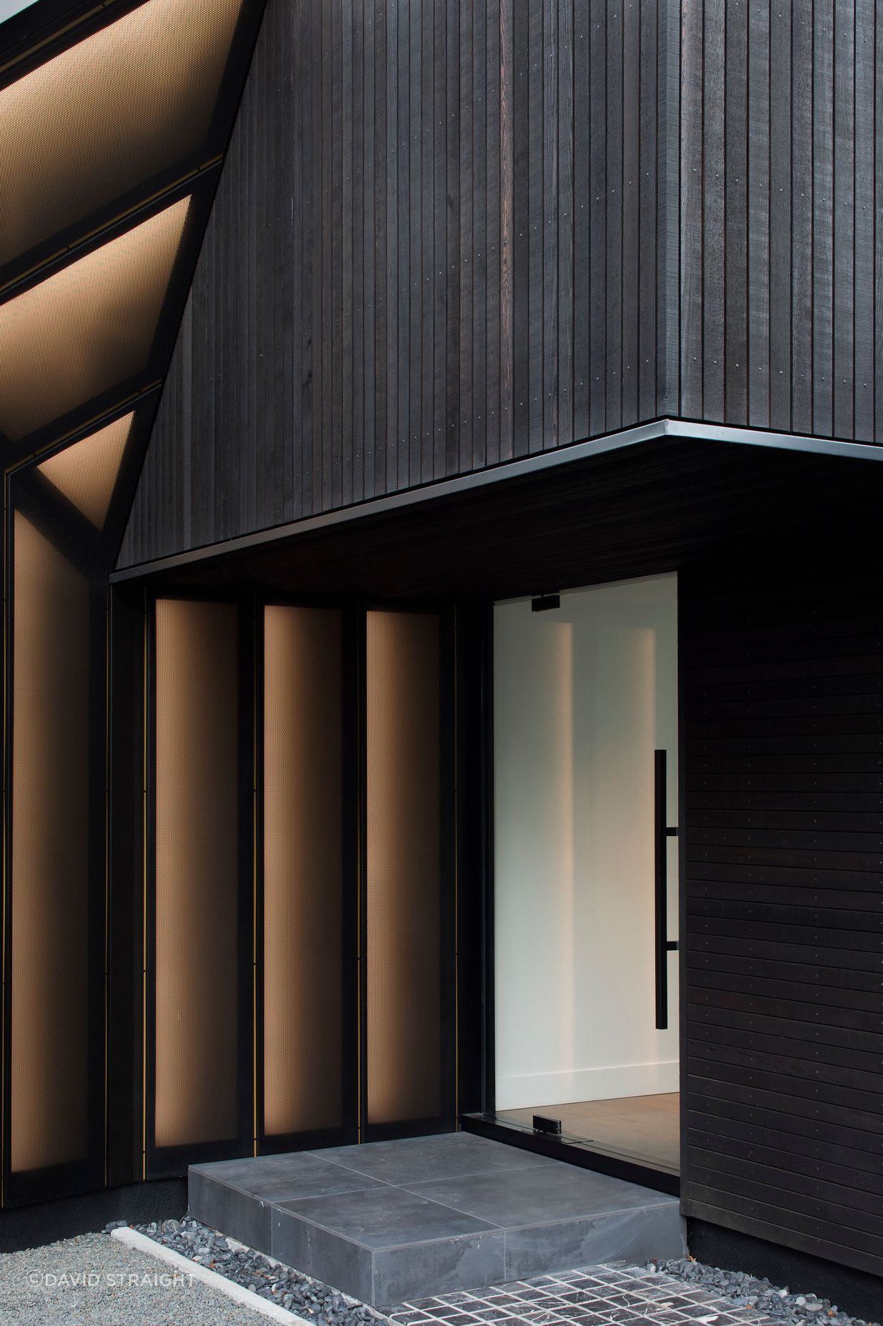 A cedar-cladd overhang provides shelter over the front entrance.