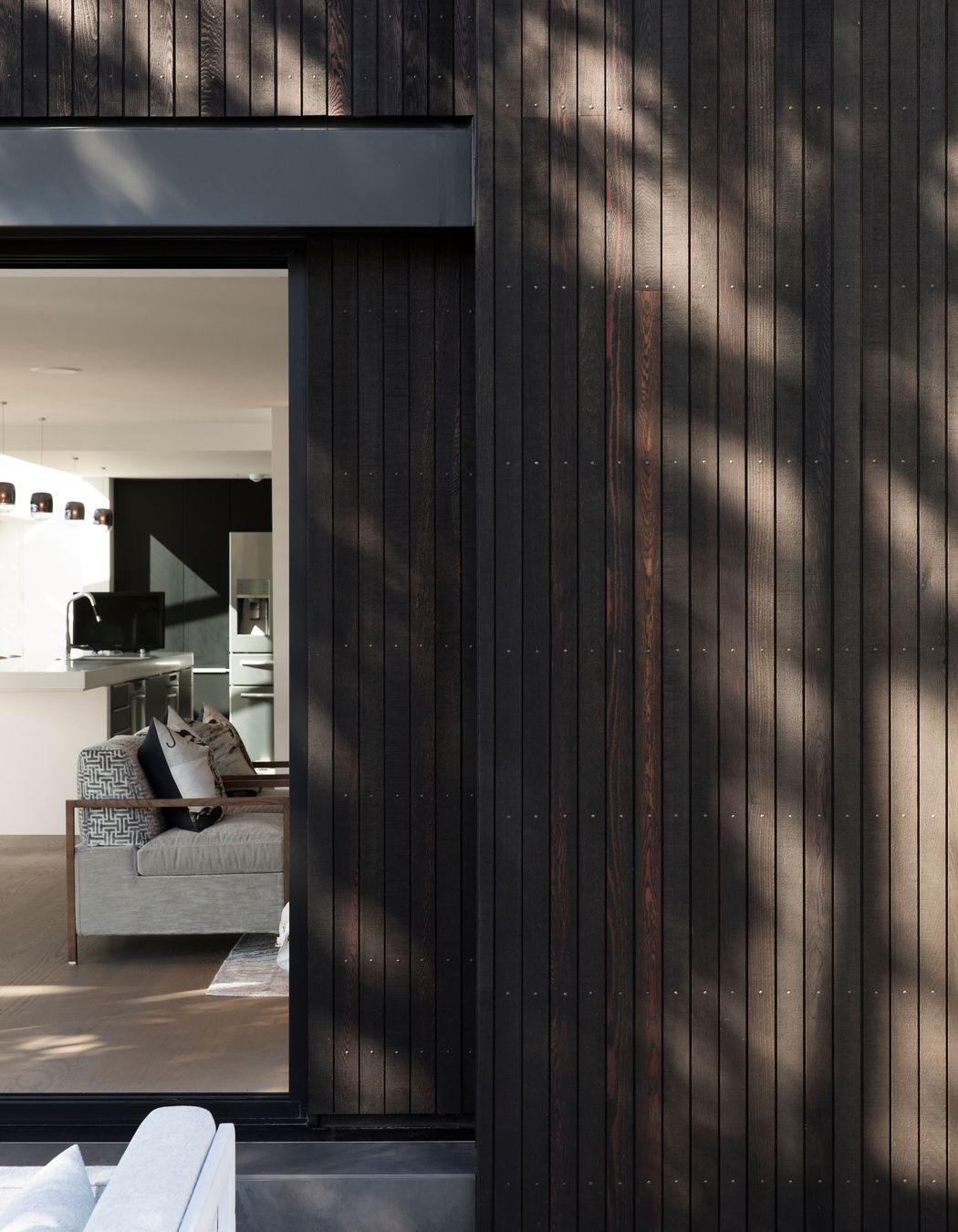 Narrow boards of black-stained cedar cladding create a pinstriped effect.