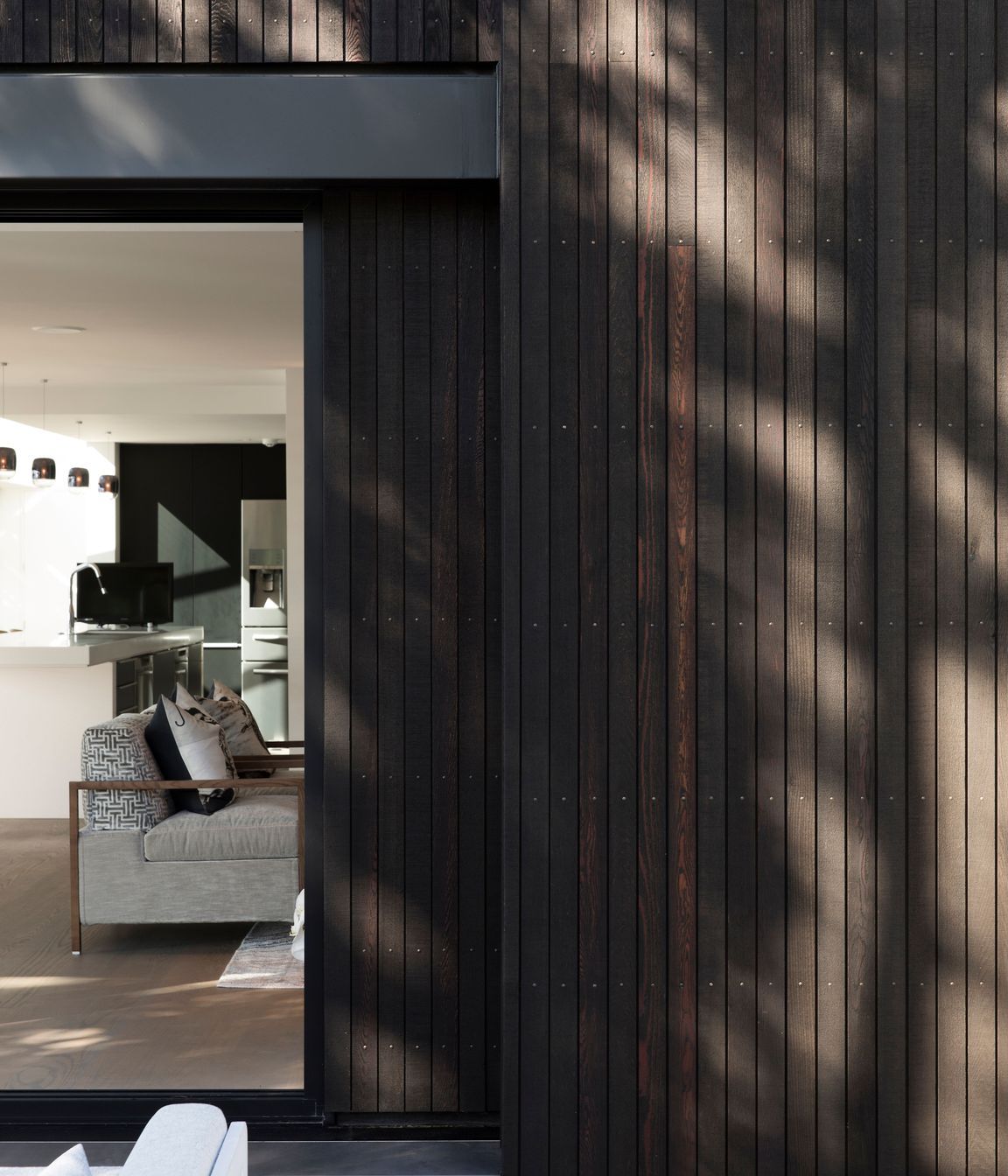 Narrow boards of black-stained cedar cladding create a pinstriped effect.