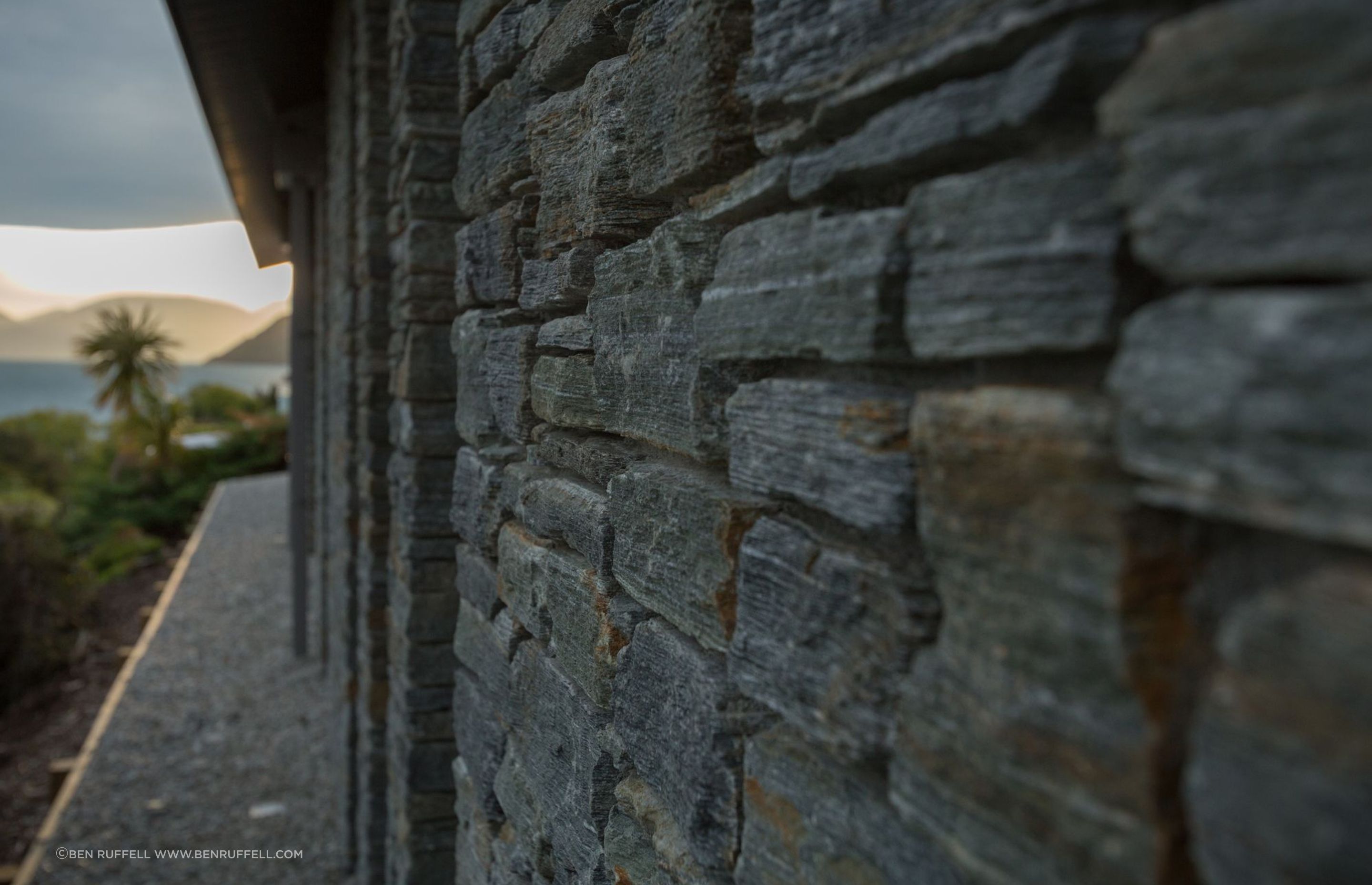 At ground level, stone walls anchor the building against prevailing winds and recognise the rock forms of the hillside.