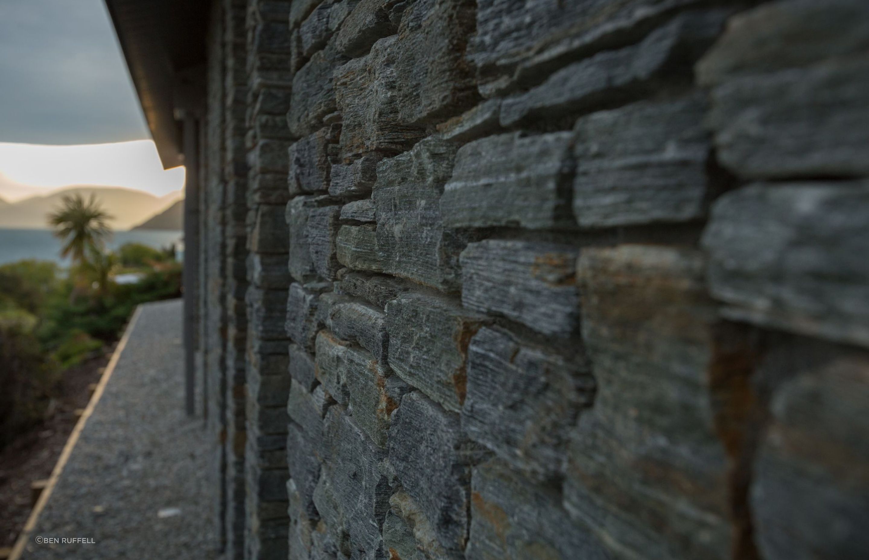 At ground level, stone walls anchor the building against prevailing winds and recognise the rock forms of the hillside.