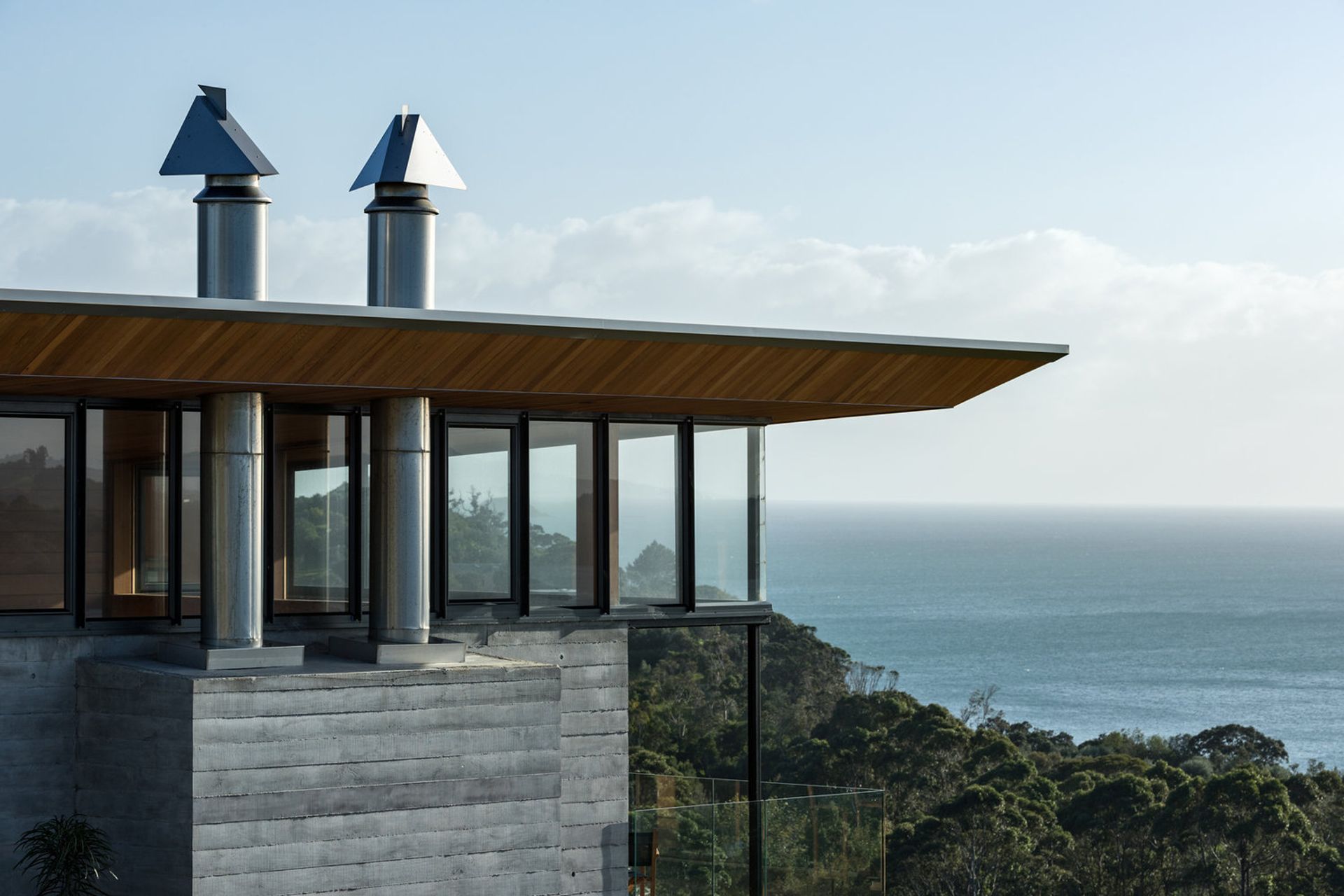 The cedar ceiling flows out into the soffit and is bevelled along the edges. helping to give the roof an appearance of floating over its solid concrete form..