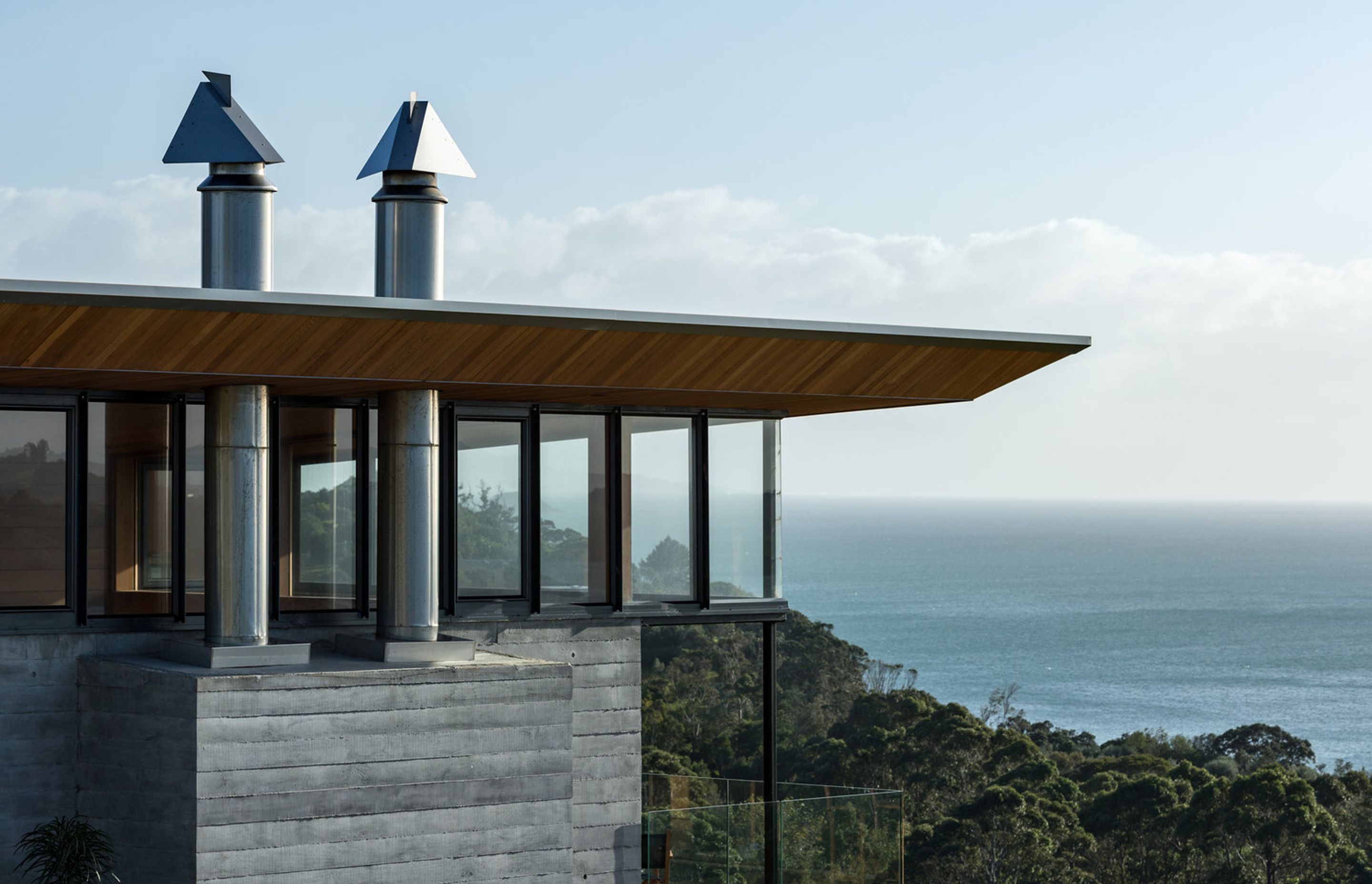 The cedar ceiling flows out into the soffit and is bevelled along the edges. helping to give the roof an appearance of floating over its solid concrete form..