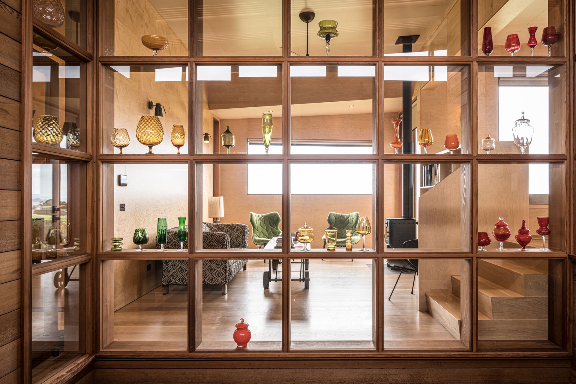 The owners’ glass art collection is showcased in this timber display case that forms the backdrop to both the courtyard and lounge. Photograph by ArchiPro.