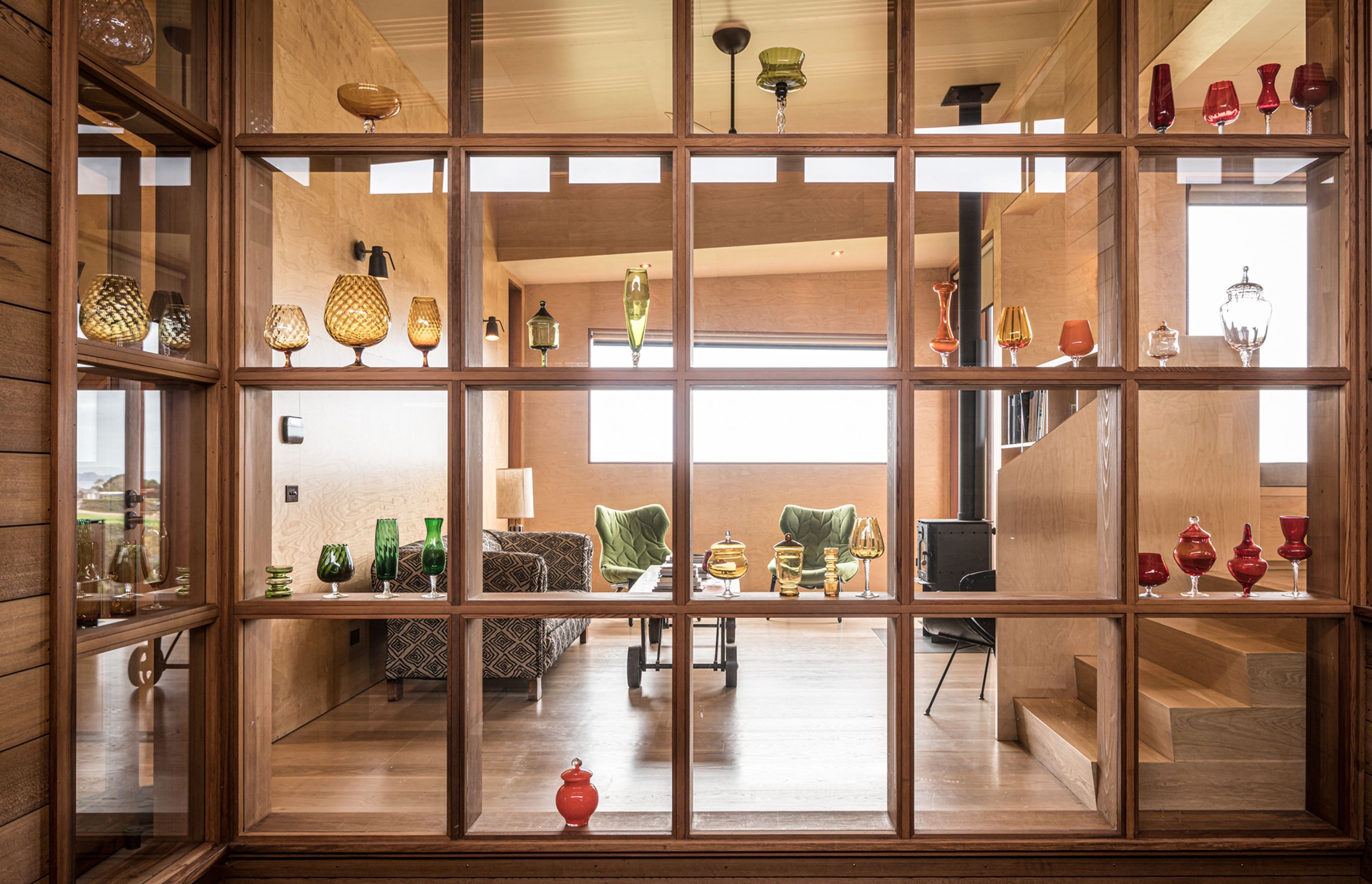 The owners’ glass art collection is showcased in this timber display case that forms the backdrop to both the courtyard and lounge. Photograph by ArchiPro.
