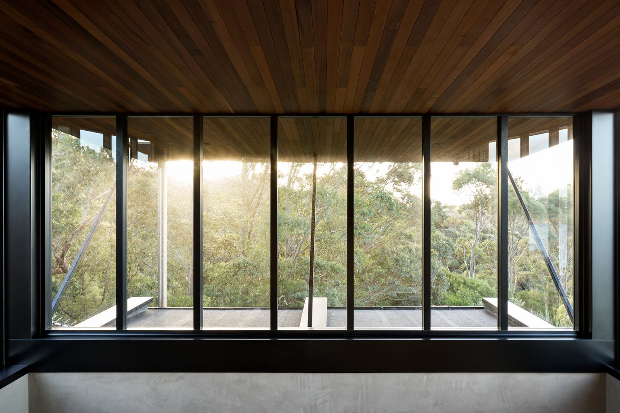 The master bedroom has a sliding window that opens up and looks north under an overhanging eave to the treetops.