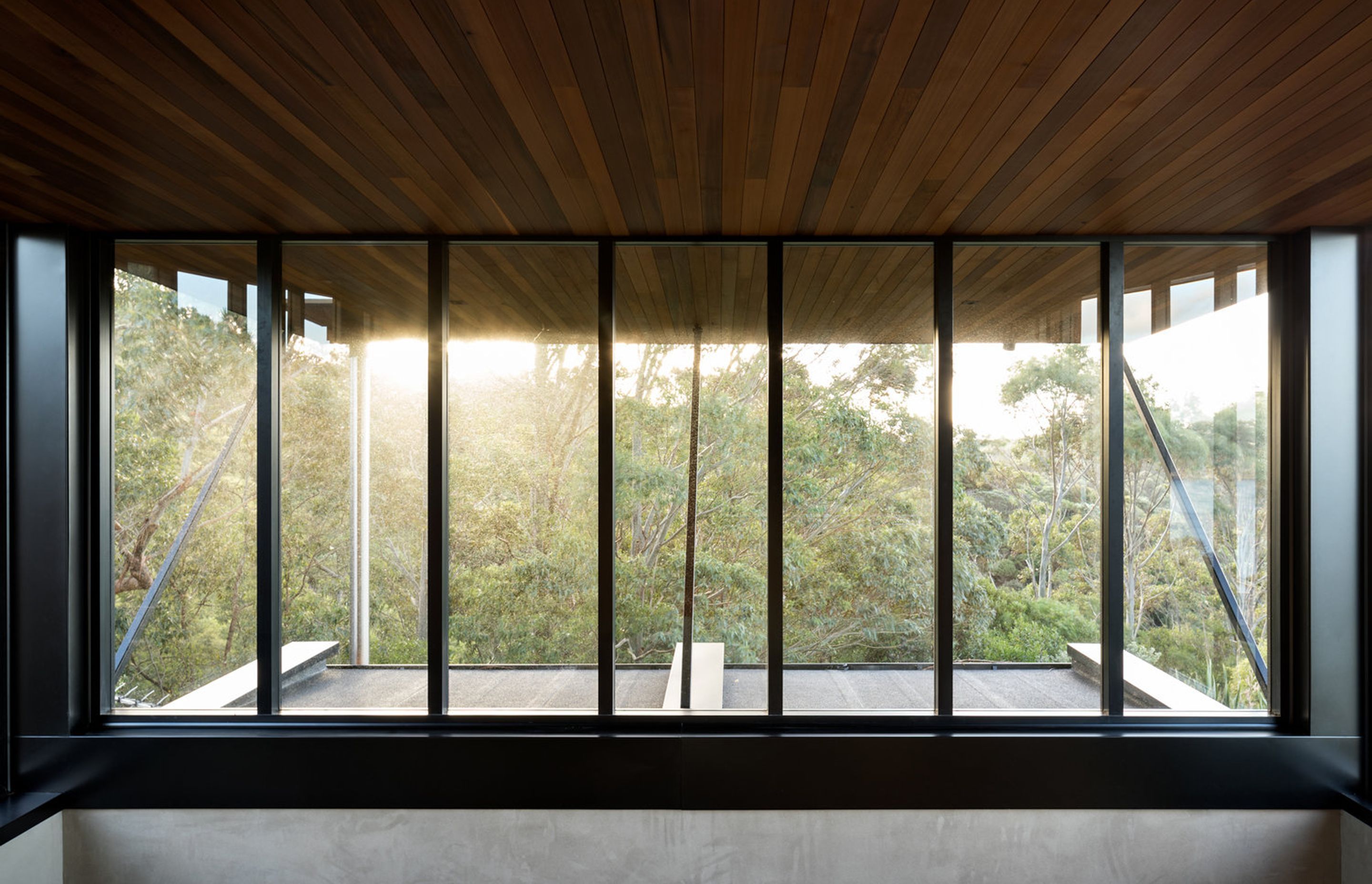 The master bedroom has a sliding window that opens up and looks north under an overhanging eave to the treetops.