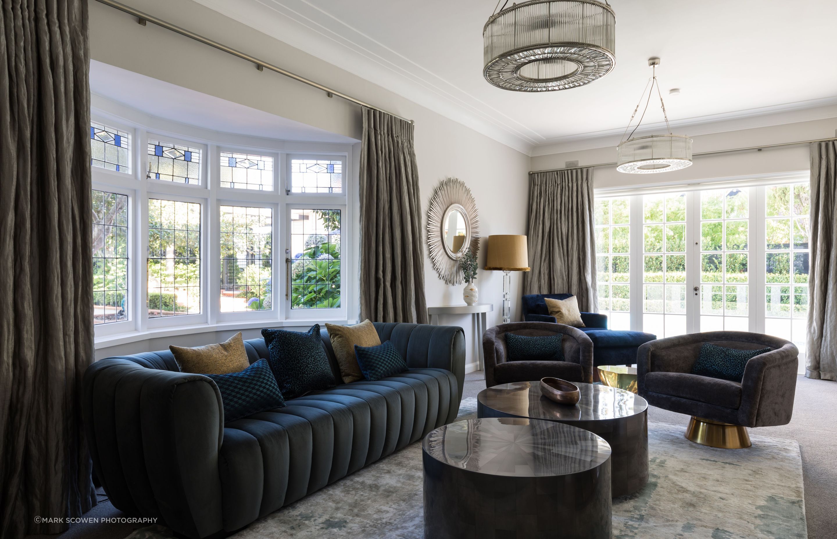 A teal three seater sofa, dual coffee tables and two swivel chairs