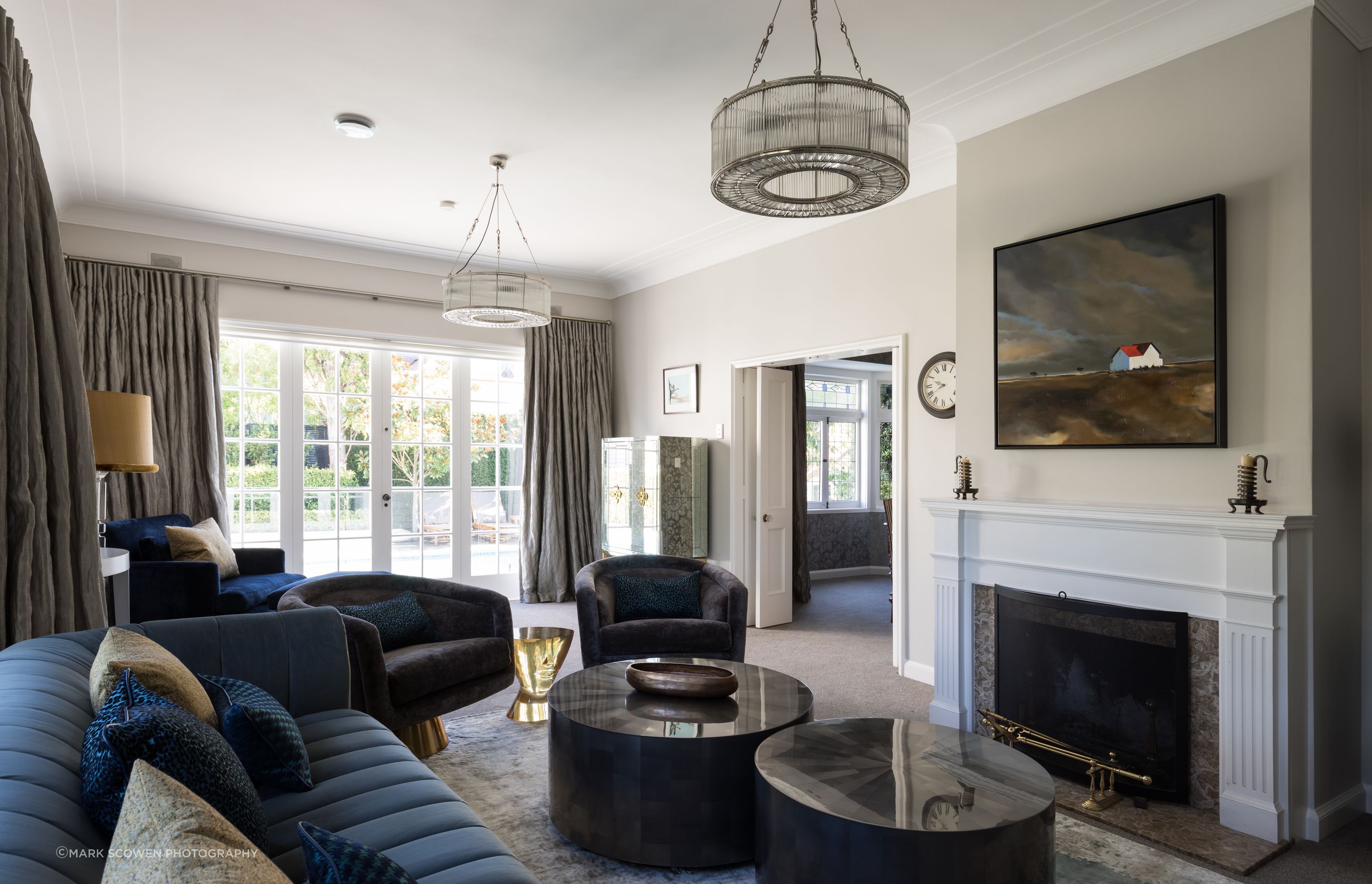 A teal three seater sofa, dual coffee tables and two swivel chairs