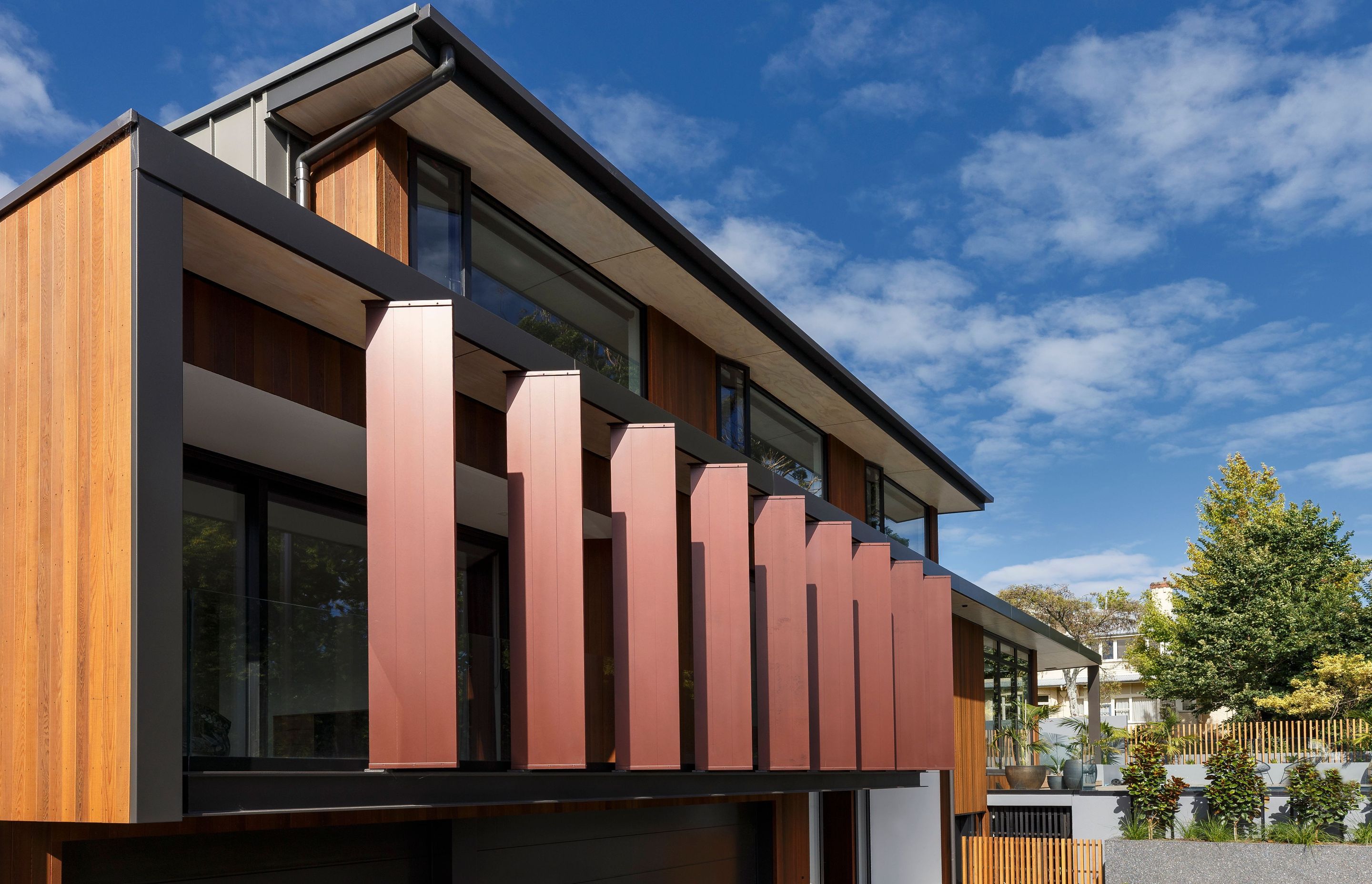 The exterior view of the front fins, painted in liquid copper to complement the warm tones of the cedar cladding.