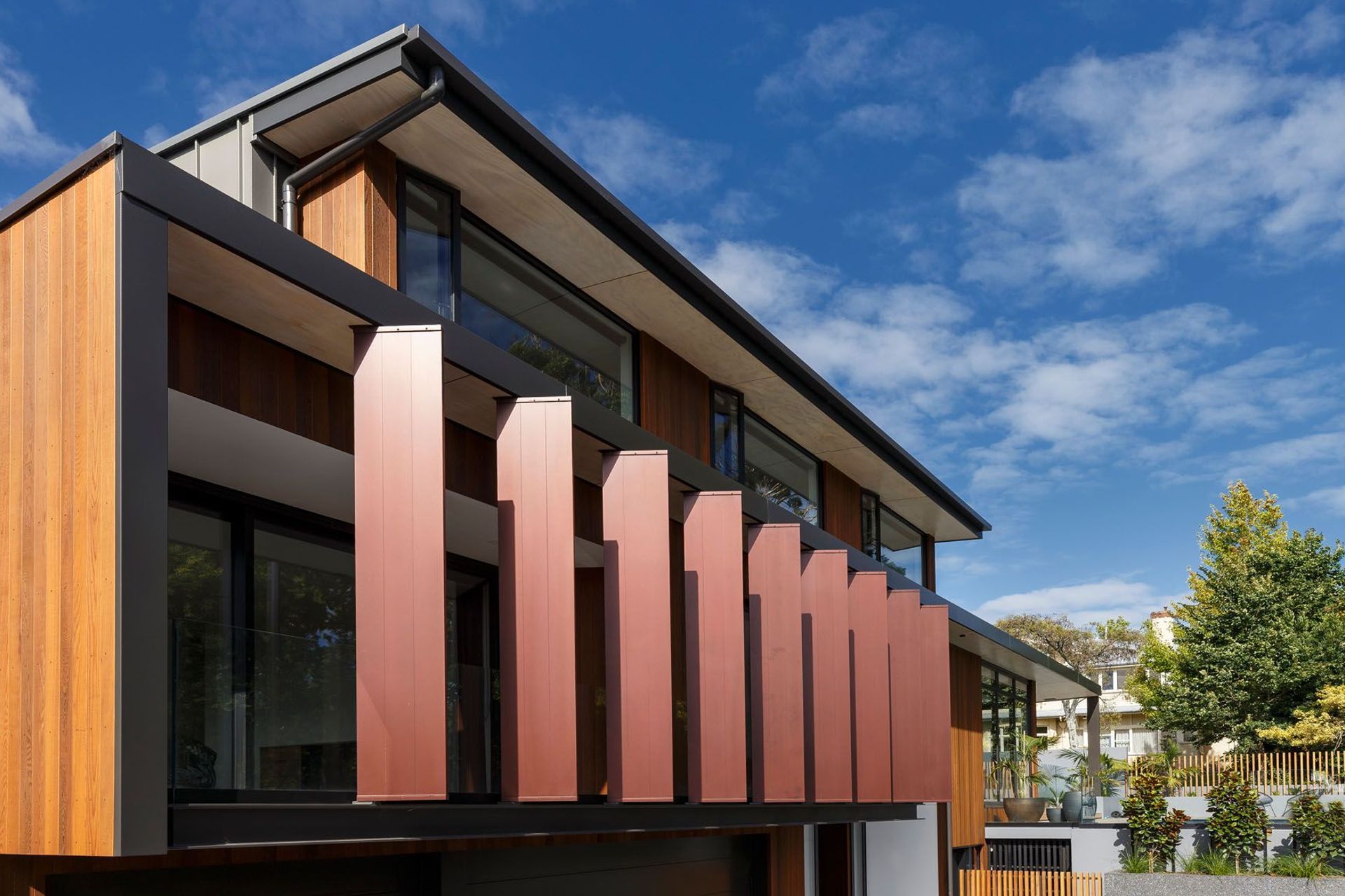 From the street, large vertical fins have been painted copper to complement the golden cedarscreen cladding.