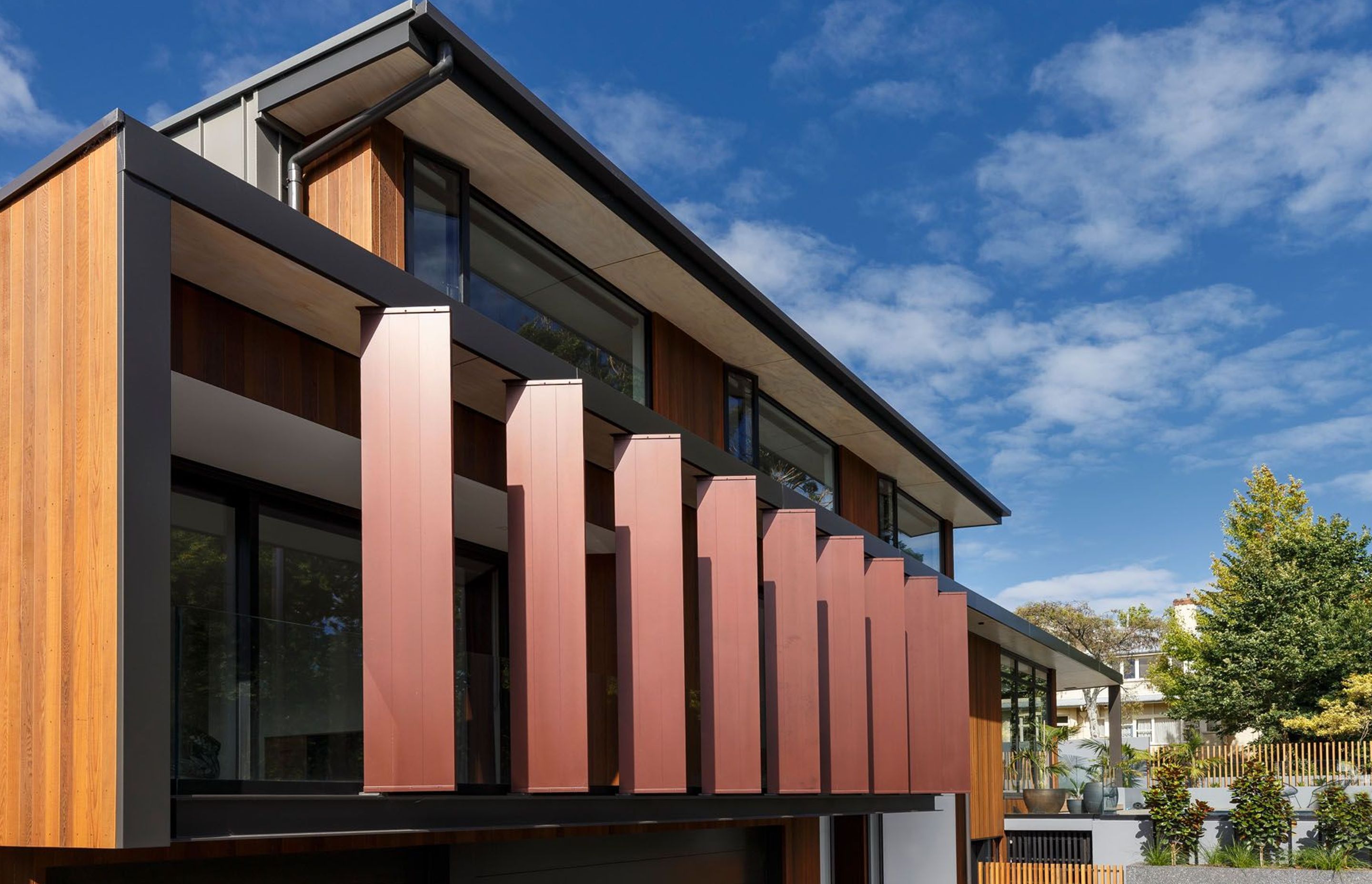 From the street, large vertical fins have been painted copper to complement the golden cedarscreen cladding.